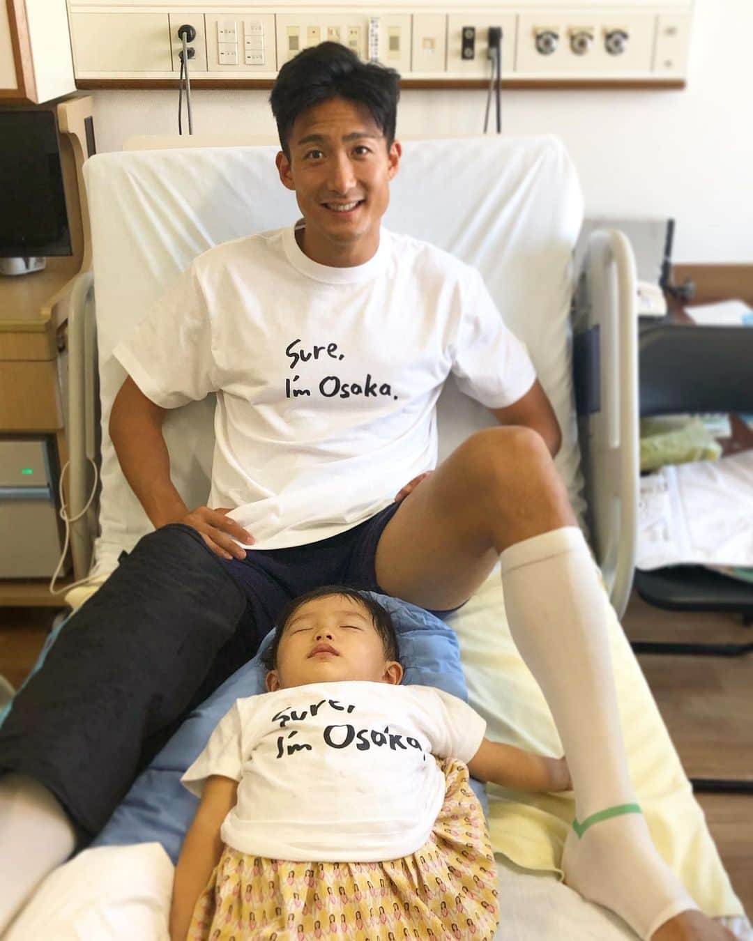 都倉賢のインスタグラム：「娘にベッド占領されるよねー🤣🤣🤣 大阪Tシャツ頂きました🙏🙏🙏 マジで想像以上に暇すぎて昼からＪリーグ3試合ぶっ通しで観てたら気持ち悪くなったんで一旦休み…笑  とりあえず今出来ることはアイシングして、足首動かして、かるーく膝動かすだけ。出来ることをちょっとずつやっていきます。  手術したから熱が38度くらいあるけど傷口が特に悪くなってるわけでないし、普通の反応みたいです！  今日から松葉杖で1人でトイレに行って良くなったのでちょっとは気が楽になりました😃  そんなこんなで病室からお届けしましたー👍  #返り咲きカウントダウン」