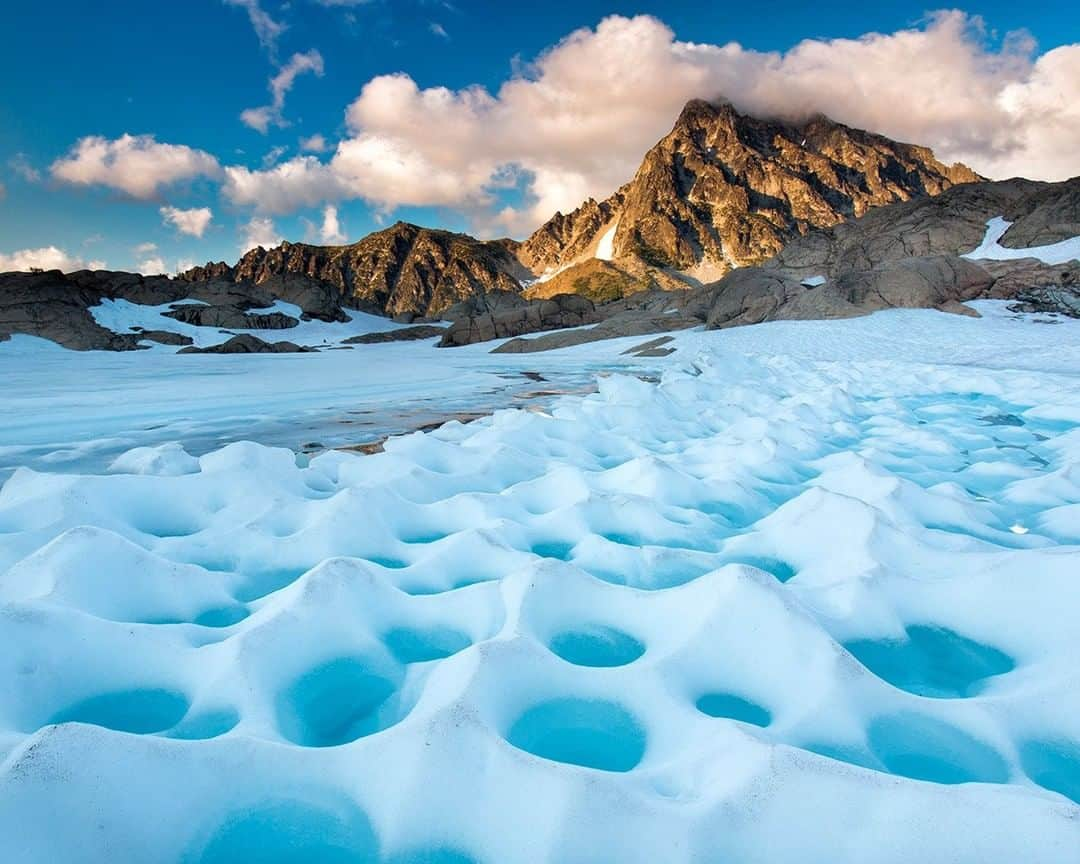 National Geographic Travelさんのインスタグラム写真 - (National Geographic TravelInstagram)「Photo @stephen_matera | Early summer snow melting on an alpine lake beneath the massive granite west side of Mt. Stuart. As the snow melts, it forms these egg carton shaped melt water pools called suncups. At 9,415', Mt. Stuart is the second highest non-volcanic mountain in Washington and the highest peak of the Stuart range, a popular hiking and climbing destination in the Central Cascade mountains. Follow me @stephen_matera for more images like this from Washington and around the world. #wilderness #snow #alpinelakeswilderness #cascademountains #snow #suncups」5月3日 22時04分 - natgeotravel