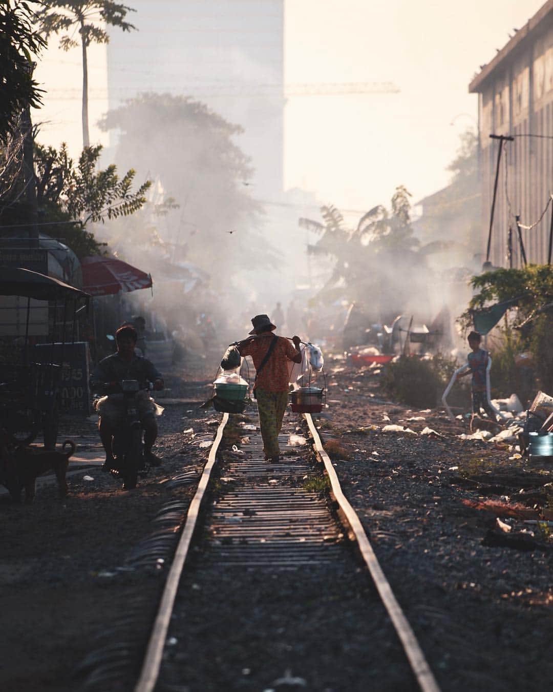 Shunsuke Miyatakeのインスタグラム：「A life on the railway, Phnom Penh, Cambodia.  Woke up before 5am and went around the railway,  with @markus.vdm and @bjoernteufel to see and feel the Raw Life.  There were robbers on Motor Cycle on the way, there were kind of drug dealers at some point, there were naked families, there were nasty garbages, there was a strong contrast between urban development and local struggling people, there were a lot of smoke coming from the burning garbages.  At the same time, there were a lot of smiles on the people's faces, there were interaction between people and pigeons, there were kids playing around, there were people sitting down together and discussing something, there were women washing the dishes with the rain water in a bucket, there were families waiting for the breakfast in the tiny hut, there were a lot of laundries hung on the air.  There's no right or wrong. There was just a life on the railway.」