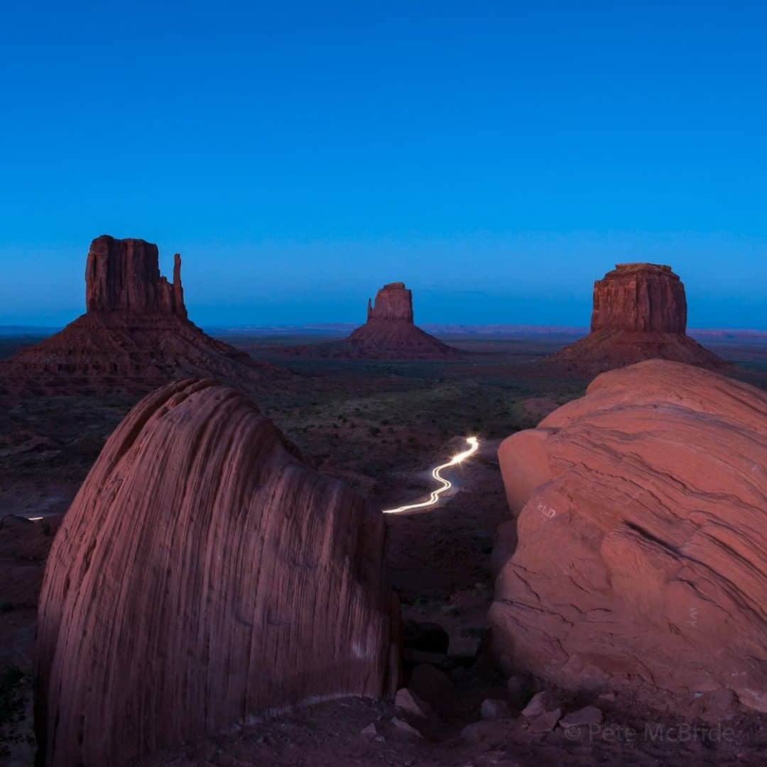 National Geographic Travelさんのインスタグラム写真 - (National Geographic TravelInstagram)「Photo by Pete McBride @pedromcbride | The dance of the blue hour falls over man-made and natural forms, casting a glow on the flow of tourists and employees leaving this valley at the end of the day. Hundreds of thousands of yearly visitors offer economic opportunities to the Navajo Nation that oversees this land, but they also bring the risk of loving the area to death. Follow me @pedromcbride for more images of natural wonders around the globe. #petemcbride #longexposure #navajo #nature #monumentvalley」5月7日 4時07分 - natgeotravel