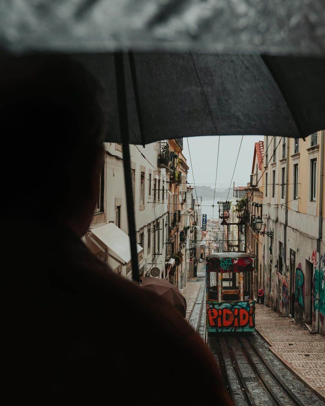 Putri Anindyaのインスタグラム：「Lisbon rainy day scenes // a week ago I browsed thru my hard disk and it came to a realisation that I have so many Lisbon pictures that I haven’t shared here. It was a wonderful day despite of the heavy rain that never stopped. Me and @capra311 were wandering around with raincoat and little umbrella that we brought from Paris. I can’t complain because i’m a lover of the rain especially in a extraordinary place like this. Let me know which slide is your favorite! :) Song video : Cela? by Graham Reynolds」