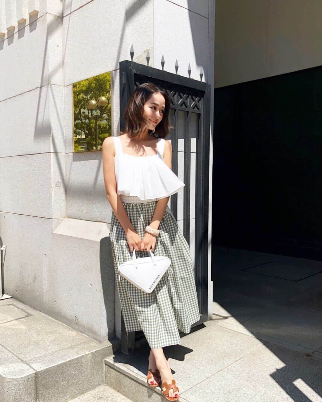 のインスタグラム：「新作ブラウスはオフショルorキャミの2way💛 二の腕を隠したいときはオフショルに。 真夏はすっきりキャミに。 立体的なフリルが可愛く仕上がりました♡ 私はギンガムチェックスカートにinしてあわせるのが好き🏝💛 . . #akiki#ss19#madeinjapan#white #coordinate#ootd#akiki_isetan」