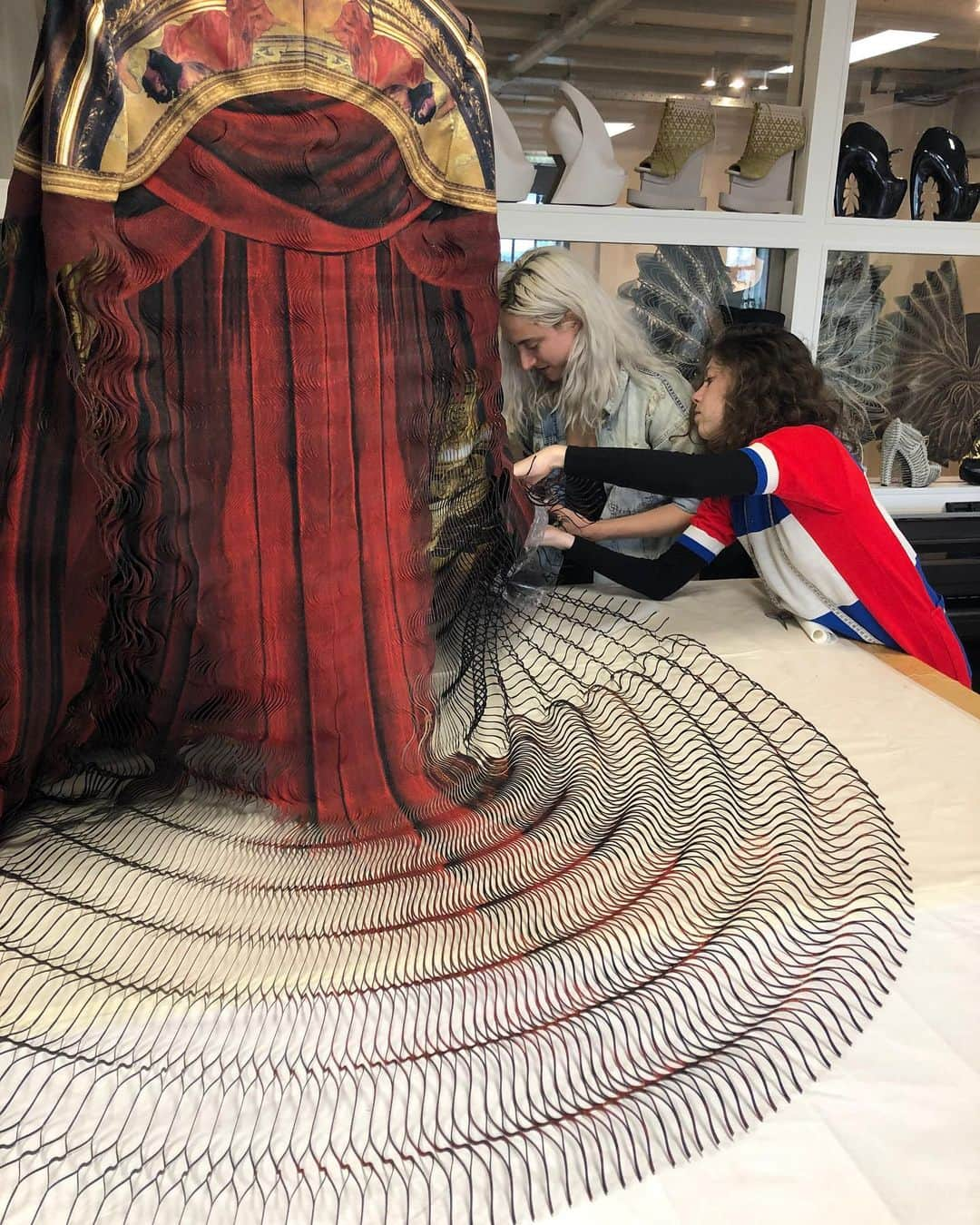 Iris Van Herpeさんのインスタグラム写真 - (Iris Van HerpeInstagram)「Behind the forms ～ a look into the intricate techniques and materials used to create @jordan_roth’s custom Met Gala costume.  To create this look, first, the outer layer was made with the ‘glitch’ delicate laser-cutting technique; each line is 0.8 mm thin, and interlinked to all the other thousands of lines by small waves. The line-design of the waves, when moving, creates a three-dimensional bubble effect and is designed to move faster than the eye can follow - therefore called a ‘glitch’. It literally tricks the eyes and mind. Classical red theatre curtains were printed onto this glitch, and are hanging from the theatre proscenium, which is a cropped tailored jacket. The waves of the red glitch can be compared to a theatre curtain, but instead of revealing the theatre when the curtains are opened, the theatre now lies in between the lines of the fabric and becomes visible when stretched. The ‘glitch' is a technique developed in collaboration with architect and professor @philip.beesley. It uses a hybrid material of cotton and mylar, first digitally printed and then heat-bonded, to finally be laser-cut into a very fine wavy web. A digitally printed silk in a spheroid pattern of 14 meters was placed underneath the ‘glitch’. Finally, a thin boning construction was created to be placed inside, so Jordan is able to extend his arm length. When he unfolds, the cape has a span width of 3.5 meters wide. ～ For the print we collaborated with the very talented photographer @davidleventi.  #metgala #metgala2019 #jordanroth #irisvanherpen」5月8日 22時41分 - irisvanherpen