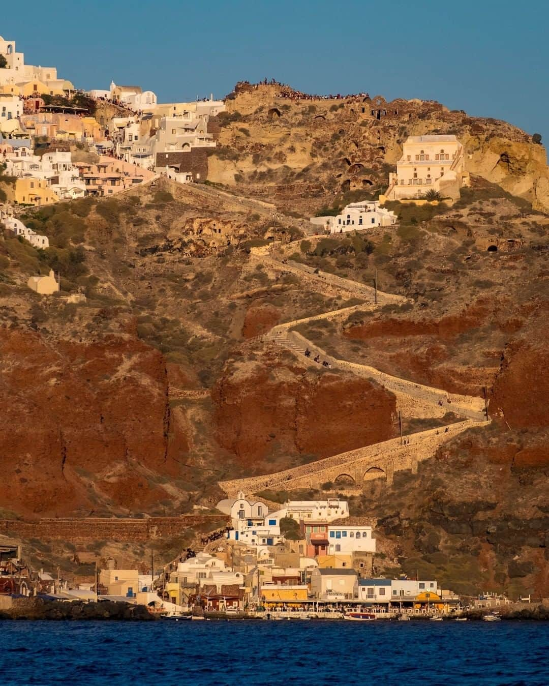 National Geographic Travelさんのインスタグラム写真 - (National Geographic TravelInstagram)「Photo by @KristaRossow | Sailing away from Santorini, I turned to see this view of the main town of Oia. The steep donkey path seemed like a graphic line leading up from the port to the top of the town where sunset-watchers looked like ants lining the caldera ridge. To see more photos from my travels, follow me @KristaRossow. #Cyclades #Greece #Santorini」5月9日 13時07分 - natgeotravel