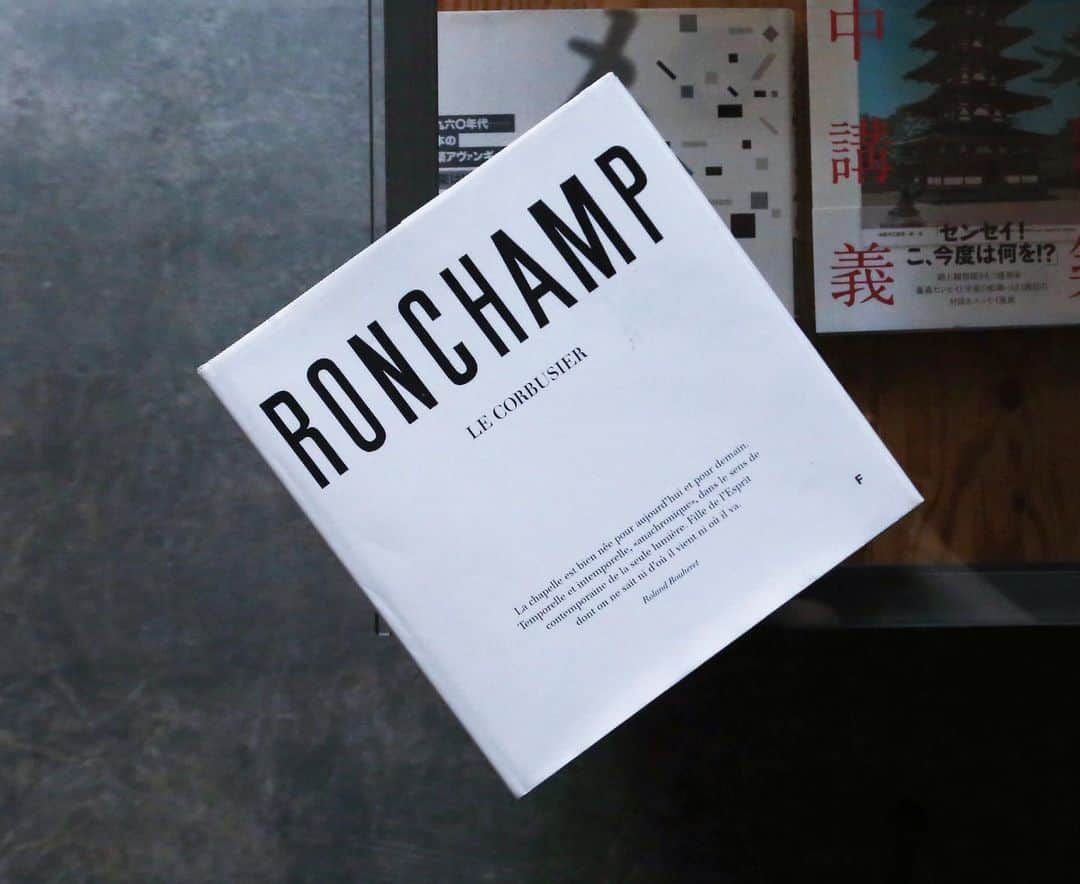 nostos booksさんのインスタグラム写真 - (nostos booksInstagram)「オープンしました。本日の #ノストスオススメ は、『Ronchamp』。﻿ ﻿ 本書は近代建築の三大巨匠として名高いル・コルビュジエが設計した、ロンシャン礼拝堂の写真集。装丁もコルビュジエ自身によるものです。﻿ ﻿ 「シェル構造の屋根に巨大な外壁、厚い壁にランダムに配された小さな開口部から漏れ入る光が…」などと説明されてもなんだかピンとこないけれど、本書に収録されたモノクロ写真を見れば、礼拝堂へ差し込む光の神々しさ、それらが壁に反射することで作り出された印影の美しさをありのまま感じ取ることができます。﻿ まるで自分の目で建築の細部を愛でて周っているかのような視点もいい。﻿ ﻿ 昨日のポストでも国立西洋美術館で開催中のコルビュジエ展について紹介しましたが、展示で氏の原点に触れ感銘を受けたという方も多いかと思います。﻿ 今度はそんな「近代の精神」がいかに昇華させたかをぜひ本書で確かめてみては。 商品の詳細はプロフィールリンクからもご覧いただけます。﻿ >> @nostosbooks ﻿ ﻿ ﻿ ﻿#ルコルビュジエ #コルビュジエ #ロンシャン礼拝堂 #コルビュジエ展 #国立西洋美術館 ﻿ #nostosbooks #本屋 #書店 #bookstore #bookshop #本 #book #books #読書 #本好き #本が好き #世田谷線 #松陰神社前」5月10日 12時49分 - nostosbooks