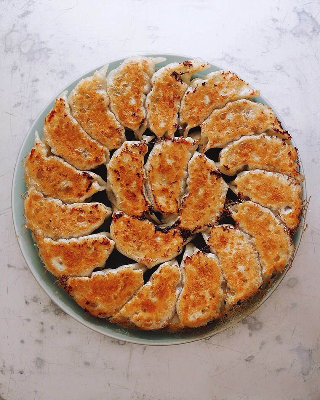 のインスタグラム：「Gyoza . 土曜のランチに餃子。 今日の具材には豚肉、 ピーマン、椎茸、葱。 夏はピーマンが推し。 . たまには包むところ 動画撮ってみました。 ヒダ１１つほどです。 皮はモランボン使用。 . . #餃子 #ぎょうざ #gyoza #dumplings #frieddumplings #dumplinggang #crispybottoms」