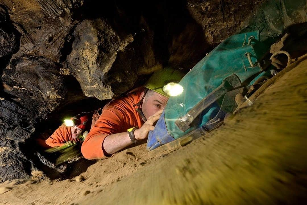 National Geographic Travelさんのインスタグラム写真 - (National Geographic TravelInstagram)「Photo by Robbie Shone @shonephoto | Not every cave in China is overwhelmingly large. Some are small.  Here, two explorers make progress along an awkward stretch of cave passage known as Where the Wind Blows, suitably named because of the strong wind that whistles through the small restriction, churning up dust and sand particles into the air and into their faces. Due to the size of the small tunnel, they are forced to push their caving sacks ahead of them., but actually this helps block out some of the sand and dust flying around in the air.」5月13日 1時10分 - natgeotravel