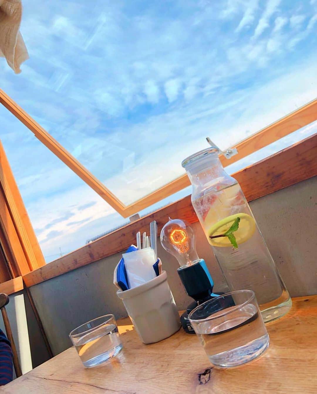 au公式Instagramアカウントのインスタグラム：「[#絶景カフェ×#スマホジェニック]﻿﻿ ﻿﻿ 大阪のカフェで撮影されたこちらのお写真は @nanasuke6.23 さんの#スマホジェニック な1枚。今回は【景色とカフェの空間を1枚に収める撮影テクニック】をご紹介します。﻿﻿ ﻿﻿ 撮影のポイントは「空が映り込む構図」と「小物の配置」。﻿﻿ ﻿﻿ とっても行きたかったカフェだったという「cafe&bakes yatt」☕️ ちょうどいい風に当たりながら、のんびりした街並みと空に﻿﻿本当に癒されたという日の写真。﻿﻿ ﻿﻿ 解放的な窓から見える空の青さがとても際立っていますね！﻿﻿ ﻿﻿ 解放的な大きな窓、綺麗な空、素敵なグラス、お店の雰囲気、﻿﻿ただただ素敵だったので、全部1枚に収めたい！という気持ちで、﻿﻿テーブルの1番端から撮ったのがポイントなんだとか✨﻿ お店にある小物を自分なりに動かして、1枚の写真に納まるようにしたんだそうです。﻿﻿ 15時頃に差し込む太陽の日差しと電球のオレンジ色の明かりも、見事にマッチしていますね♪﻿﻿ ﻿﻿ ぜひこちらを参考にして、皆さんも#絶景カフェ の素敵な一枚を撮影してみてくださいね！﻿﻿ ﻿﻿ ﻿﻿ photo by @nanasuke6.23﻿﻿」
