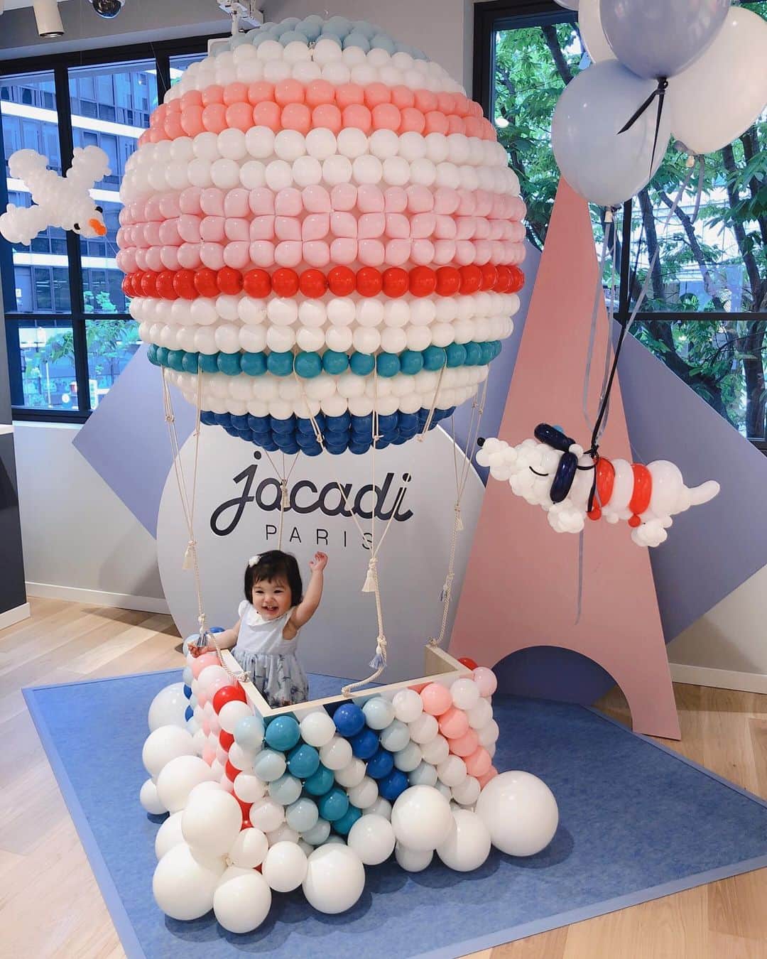 倉窪莉沙のインスタグラム：「* JACADI × EMI JINGU BALLOON 大好きな子供服店jacadiに期間限定でバルーンアートが展示されていると公式のインスタグラムで知り、神戸店へ行ってきました🐶🎈💓娘も可愛いバルーンアートに興味津々😍最近習得した「はーい🙋‍♀️」を披露しながら記念撮影させていただきました💗母も楽しくお買い物ができて大満足！可愛いワンピース、着るのが楽しみだね💕💕 #jacadi #jacadiart #jacadikobe #バルーンパフォーマンス #バルーンアーティスト #神宮エミ . . #女の子 #girl #女の子ママ #1歳 #4月生まれ #平成生まれ #コドモノ #コドモダカラ #ベビフル #スマイル育児 #ママカメラ #神戸 #kobe」
