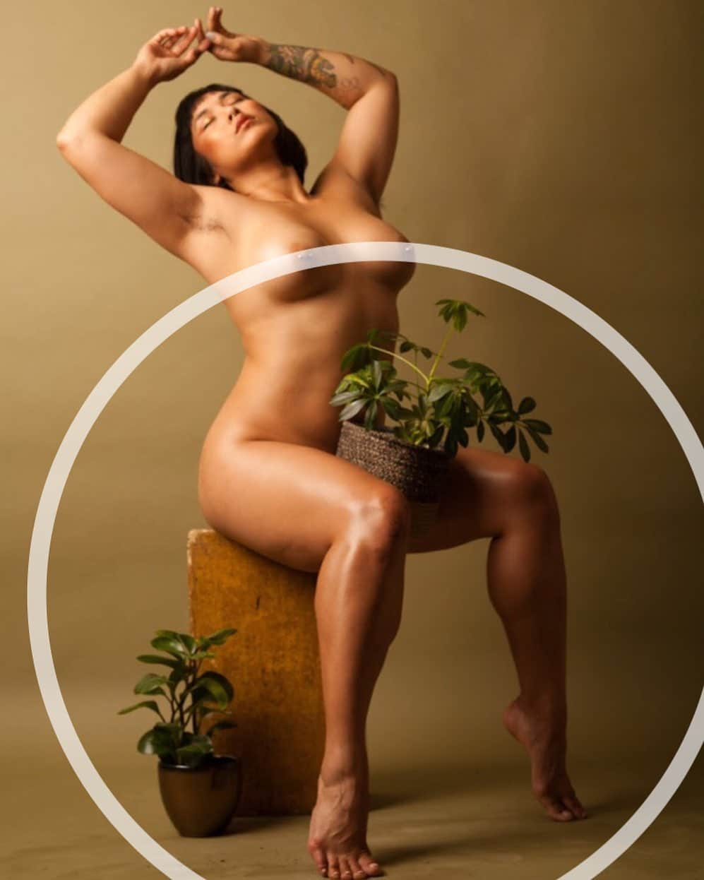 Mia Littleのインスタグラム：「Growing and Glowing and Contemplating gender shot by @taryncarterphoto [photo description: Mia sitting on top of an apple box with a plant in a basket resting between their legs. Their toes are pointed, their back is arched. Mia sits with their arms stretched above her head. Her/their eyes are closed. An opaque white circle censors their nipples but cuts out of frame.]」