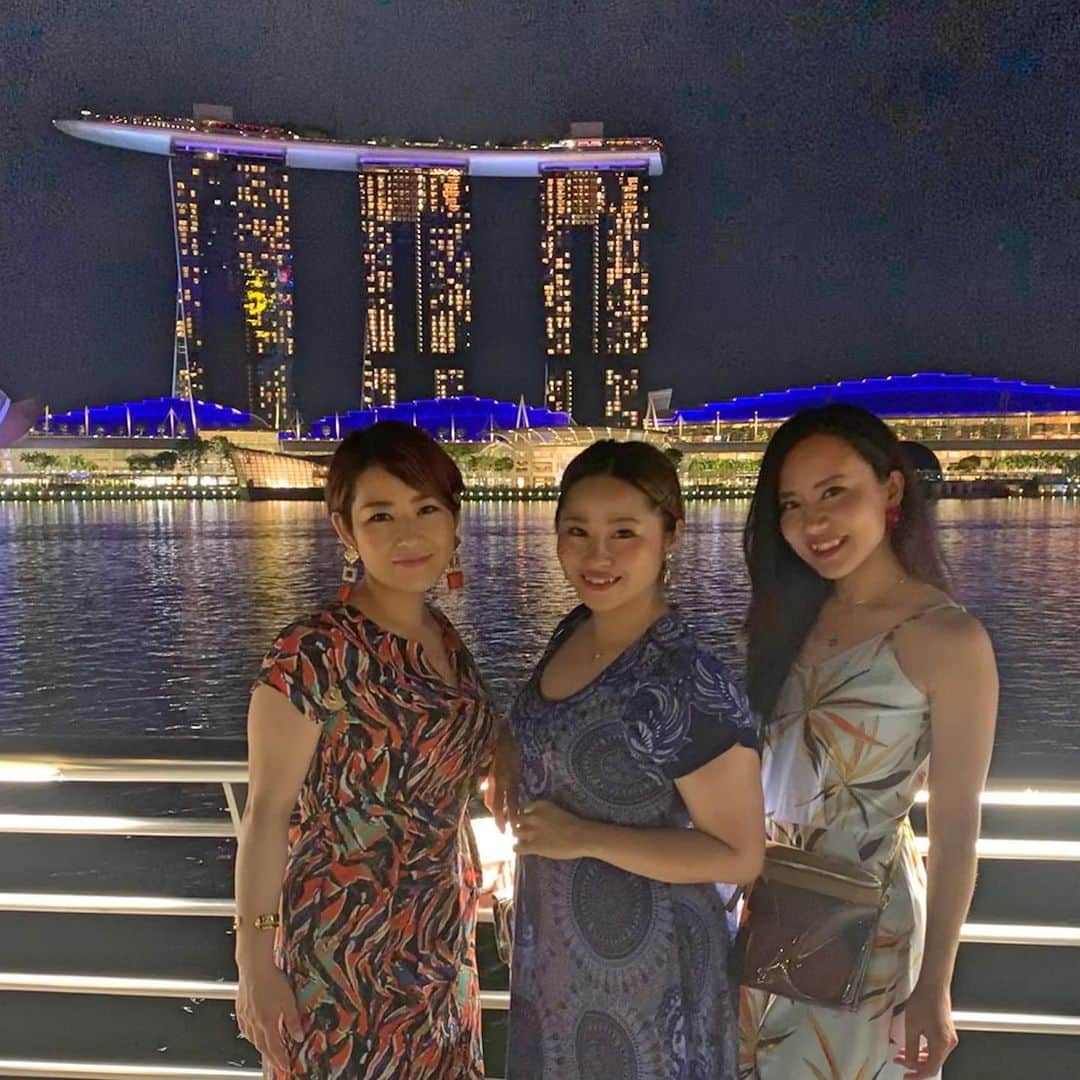 長嶺菜菜子のインスタグラム：「✈︎シンガポール観光  マリーナベイサンズってさ﻿ 歪んでるよね( '∀︎' )﻿ ﻿ ﻿ 私たちが泊まったレベル3のビルは1番歪んでいるのだと( '∀︎' )﻿ 写真でいう船の先端に近いビルの事ね﻿ ﻿ ﻿ このホテル作った人尊敬するわ🤩🙌🙌﻿ ﻿ ﻿ マリーナベイの周りは﻿ マリーナベイサンズに始まり﻿ 高層ビルも立ち並び﻿ マーライオン公園があり﻿ ﻿ ﻿ すんごくすんごく発展していてキラキラしていて﻿ ステキなとこだった(♡︎ˊ艸ˋ♡︎)﻿ ﻿ ﻿ うちら3人もおめかしして出てきた甲斐があったわ😚✨✨﻿ お気に入りの赤のピアスが映えてるぜ﻿ Piercing... @roomx601 ﻿ ﻿ ゆっくりマリーナベイサンズを眺めながら﻿ 飲みたいな﻿ ﻿ ﻿ 物価高めだから飲み過ぎ注意なんだけども🤭﻿ ﻿ ﻿ ﻿ ﻿ 写真撮ってたら﻿ インド人の家族と仲良くなって﻿ 一緒に写真撮ろって言ってくれて﻿ 旦那さんのサムスンの携帯で撮ってくれたのね﻿ ﻿ ﻿ めちゃくちゃカメラの性能良くてさ﻿ 夜なのにすんごく綺麗に撮れてて﻿ iPhone負けてるやん🤐🤐﻿ ﻿ ﻿ #旅行 #旅 #旅女子 #旅行好き ﻿﻿﻿#女子旅﻿ #タビジョ #シンガポール #シンガポール観光﻿ #シンガポールホテル #マリーナベイサンズ夜のショー #光と水のスペクタクルショー﻿ #マリーナベイサンズ ﻿ #roomx601 #roomxaccessory #chao_app #ボヤジンフォトコン秋2019 #旅なな」