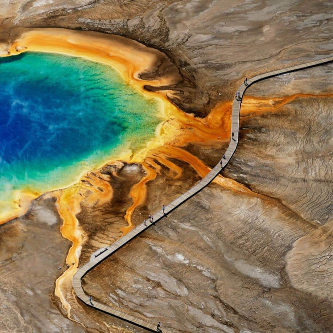 National Geographic Travelさんのインスタグラム写真 - (National Geographic TravelInstagram)「Photo by George Steinmetz @geosteinmetz | Swipe right to see visitors to Yellowstone National Park stroll along a boardwalk near the edge of Grand Prismatic Pool, a natural hot spring. At the center of the pool is 93°C mineral water, which cools as it nears the edges of the pool. The different colors are caused by bacteria that live in different temperatures of water. To view more of our earth from above, follow me, @geosteinmetz.」6月22日 4時19分 - natgeotravel