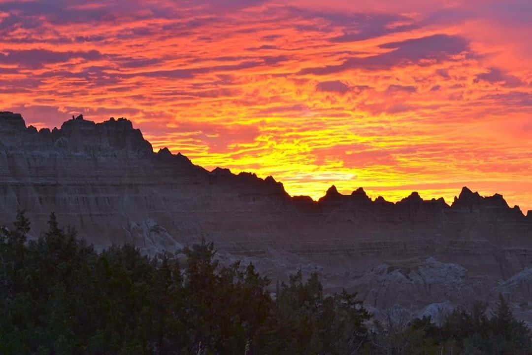 アメリカ内務省さんのインスタグラム写真 - (アメリカ内務省Instagram)「Sunrise over Badlands National Park in #SouthDakota reveals a landscape of grassy prairies and rugged rock formations. The rock layers testify to tens of millions of years of deposition -- when tiny grains of sediments such as sand, silt and clay are cemented together into rock. Different environments -- sea, tropical land and open woodland with meandering rivers -- caused different sediments to accumulate here at different times. About half a million years ago, the process reversed itself and now water and wind erode the rocks, leaving behind this jagged silhouette and its embedded #fossil treasures. Photo by #NationalPark Service. #usinterior #FindYourPark」6月18日 0時19分 - usinterior