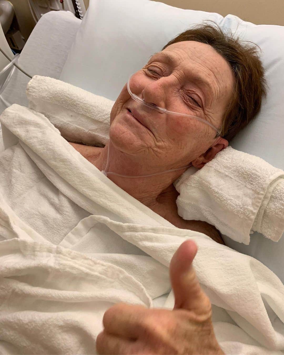ケヴィン・スミスのインスタグラム：「Mom is out of surgery! She’s groggy and sore from where tubes were, but otherwise a-okay! The Watchman device - which was designed to close the left atrial appendage in her heart in an effort to reduce the risk of stroke - was placed successfully! While up in her guts, the Doctor discovered Mom’s ticker is larger than the average ticker. I didn’t need it medically proven to me to know my Mom’s got a big heart: I’ve been on the receiving end of her affection my entire life. @virginia_in_vienna has been reading her your kind comments and my Mom with the oversized heart wants you all to know she is incredibly touched by your positive vibes. The stuff you took the time to write is providing post-surgical smiles! This is the very first Kevin Smith fan that ever existed - so Grace is my Base! I need her to stick around for a very long time. Long Live the Legion and Long Live All Moms! #KevinSmith #gracevsmith #mom」