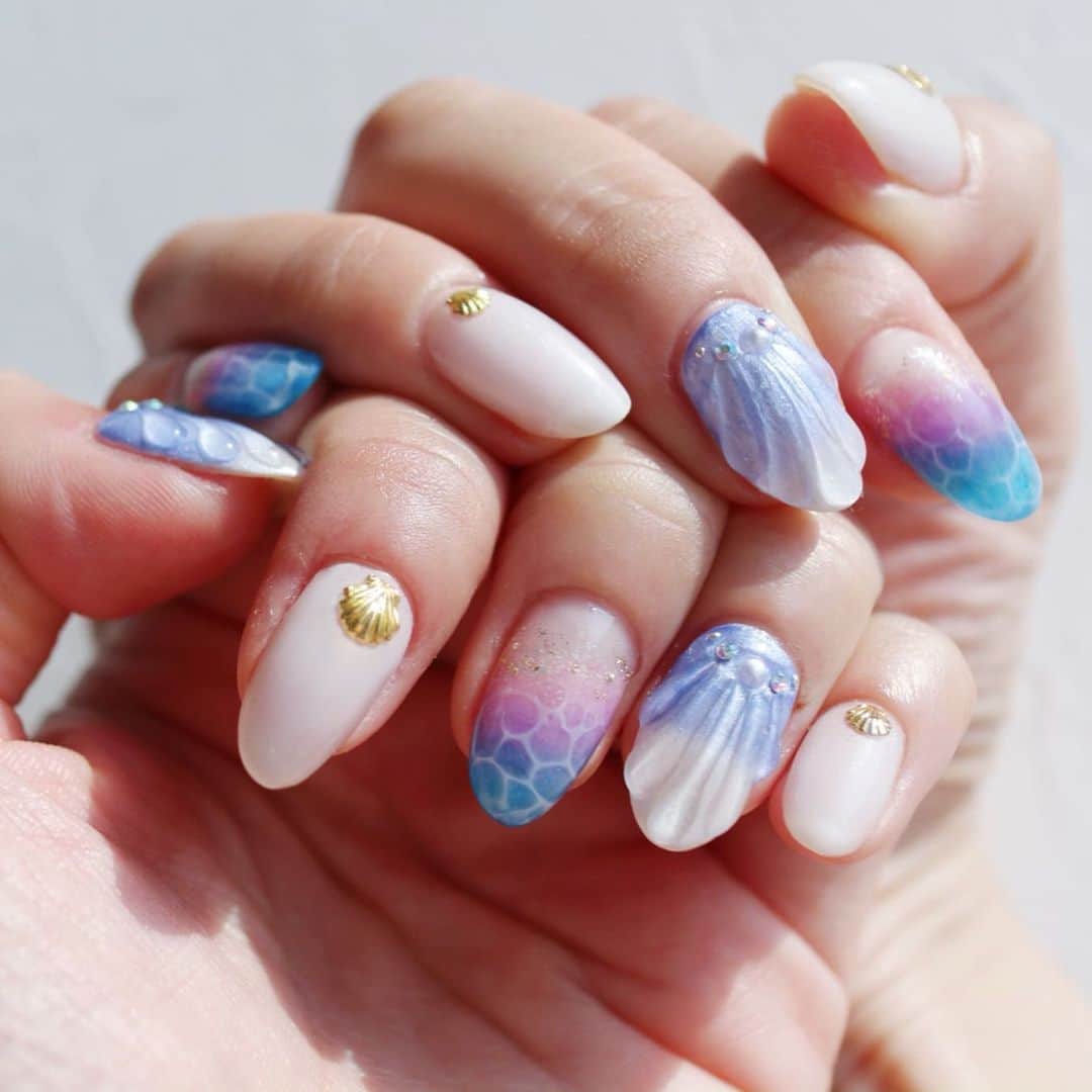 リナのインスタグラム：「すでに周りのお友達から大好評の #人魚の鱗ネイル 🧜‍♀️ . 今回は、ネイリストさんのやりたいことを満載に詰め込んで頂きました🌟 . #人魚の鱗ネイル に#ドロップネイル  が本当に夏らしくて可愛くて… ネイルを眺めているだけで、 潮風を感じられちゃいます🏖 . ホワイトの#ワンカラー もパールがチラついていて、 絶妙なんです😍 . ぷっくりツヤツヤでどこから見ても非のうちようのない 仕上がり👑 「ツメがのびなきゃいいのに〜！」って本当に思える仕上がりなんです♡♡ . ネイルを通じて、 新しい出会いや家族や友達との会話や笑いが増えるなんて、 ネイルって奥深いですね〜💅 . @nanamilk.nail @nail_sugar_yuka  ステキな機会をありがとうございました😊♡ ........................................................... #ネイルデザイン #ネイルアート #ジェルネイル #nail #nailstagram #jelnail #マーメイドネイル #ドロップアートネイル #水面アートネイル #水面アート #ホワイトパールネイル #夏ネイル #サマーネイル #涼しげネイル #リゾートネイル #3児ママ #ナナミルク #シェルネイル #ネイル好きな人と繋がりたい #ネイル好き」