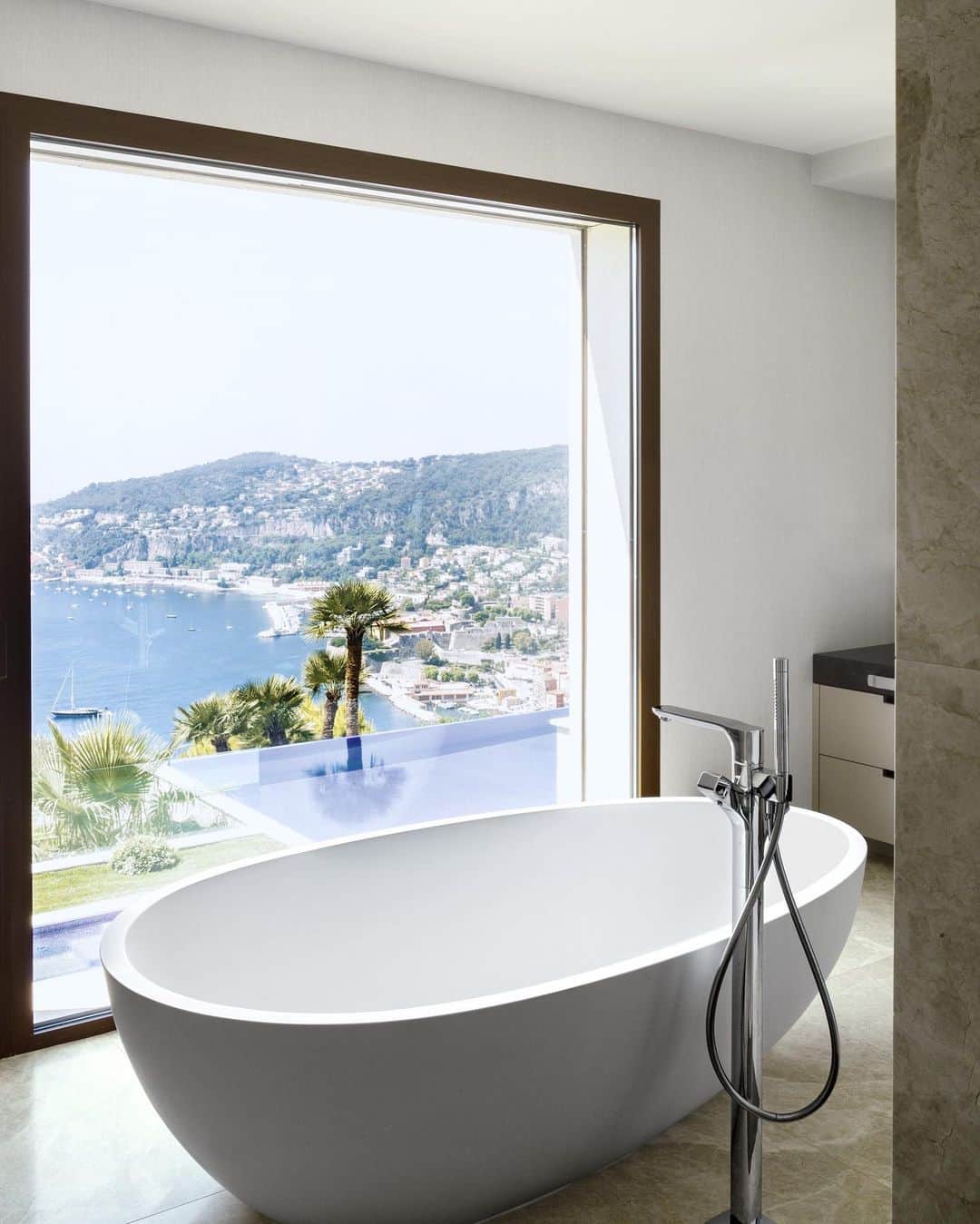 ELLE DECORさんのインスタグラム写真 - (ELLE DECORInstagram)「An Agape soaking tub in the master bath of fashion designer @lisaperrystyle’s home on the French Riviera overlooks the Bay of Villefranche. Perry’s love of 1960s fashion, art, and furniture helped inform the design of her airy Côte d’Azur retreat, as seen in our June 2019 issue. Click the link in bio for the full tour. Photo: @robynleaphotography」5月29日 0時53分 - elledecor