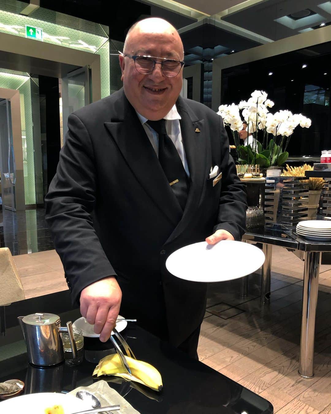 スコット・シューマンのインスタグラム：「This is important! This is elegance and efficiency! This is why I stay at @excelsiorhotelgallia !  So I’m having breakfast (mainly fruit) and out of the corner of my eye the maitre’d swoops by like an eagle 🦅 with a pair of tongs and a plate, picks up my empty banana peel and whisks it away! Chic! I’ve never seen that and yet it makes total sense (he doesn’t want his hands smelling like banana!) a rotting banana peel doesn’t look or smell good in his dining room. This is also the essence of Milan at its old world best ! Subtle and chic, how can we do things the most effectively while also making the act of it a graceful gesture! The funny and touching part is I ask him to do it again and he couldn’t understand what I was asking, it’s not a big fake gesture to him but just pride and self-respect for his job and his guests. I know @marriotthotels recently took over the hotel and I beg that they cherish people like him for the inspiring way they do their job everyday (even on the little things they think we don’t notice!) Bravo!」