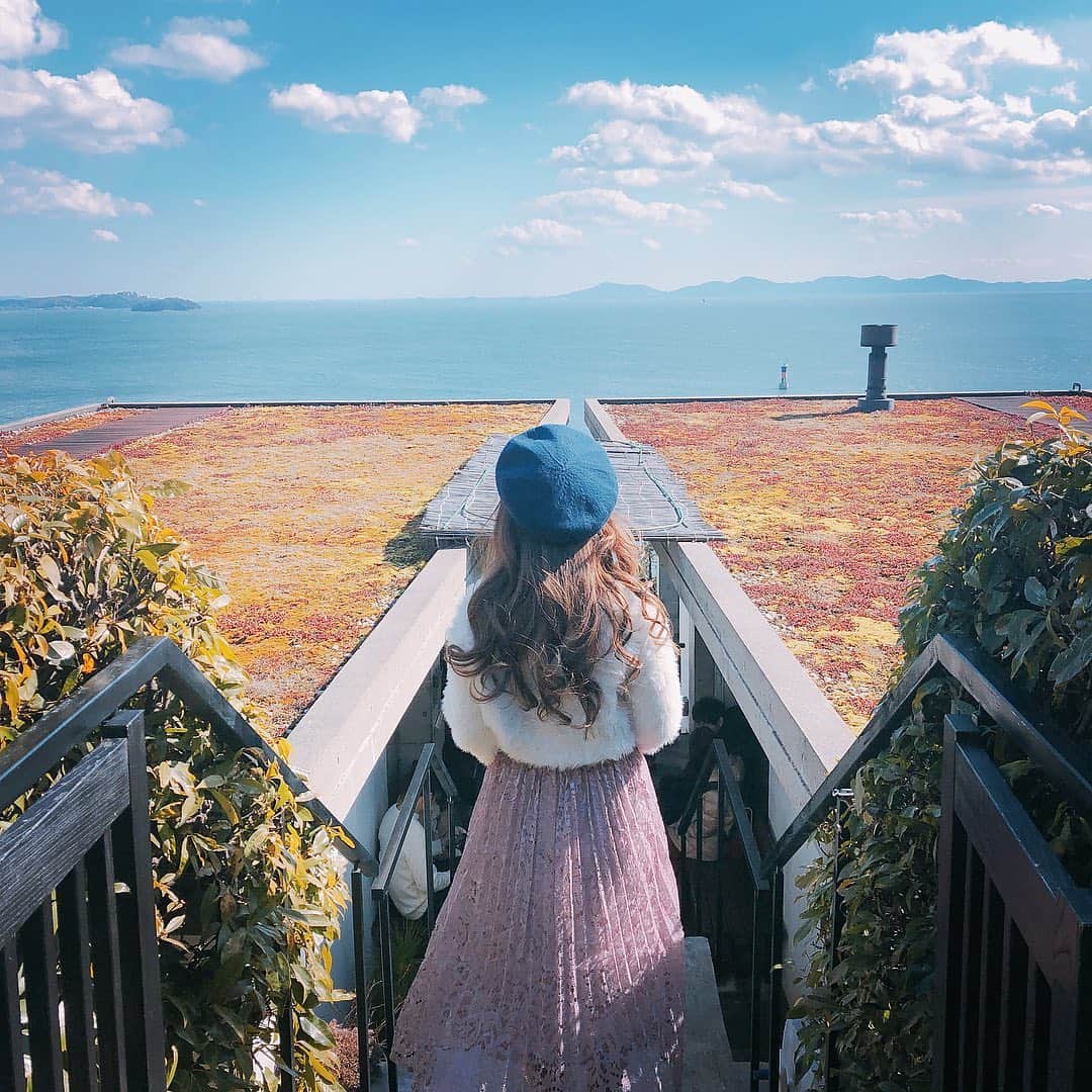 au公式Instagramアカウントのインスタグラム：「[#絶景カフェ×#スマホジェニック]﻿﻿﻿ ﻿﻿ 三河の海が臨める愛知県にあるカフェで撮影されたこちらのお写真は @honoka.59 さんの#スマホジェニック な1枚。今回は【物語を感じさせる撮影テクニック】をご紹介します。﻿﻿﻿ ﻿﻿ 撮影のポイントは「色鮮やかな加工」と「撮影時のアングル」。﻿﻿﻿ ﻿﻿ 撮影時のカメラアプリは『Foodie』を使用。色彩がはっきりするので、背景を綺麗に鮮やかに映したい時に使うのだそう✨被写体の位置は、海へと繋がる道の真ん中にくるよう、撮影者に指示してもらいながら撮影したんだとか。また、正面からの撮影ではなく、あえて「後ろ姿」にしたという撮影のアングルも、雰囲気のある写真にするためにこだわったポイントだそうです！﻿﻿ 更に、投稿を見た人が写真から物語を感じられるようにするため、遠くを見つめている姿を写真に収めたという工夫のお陰で、とても情緒を感じられるお写真になっていますね！﻿ ﻿﻿﻿ ぜひこちらを参考にして、皆さんも#絶景カフェ の素敵な一枚を撮影してみてくださいね！﻿﻿﻿ ﻿﻿ ﻿﻿ photo by @honoka.59 ﻿﻿」