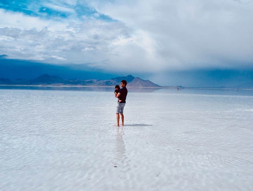 香山ひとみさんのインスタグラム写真 - (香山ひとみInstagram)「#アメリカ生活国内旅行編 Bonneville Salt Flats . 先日のメモリアルデー休暇を利用して、 イエローストーン＆塩湖旅行に行ってきました✈️✨ . まずは、ユタ州にある塩湖、 【ボンネビル・ソルトフラッツ】へ。 せっかくアメリカにいるし、一度は南米ボリビアのウユニ塩湖へ行きたい...😭と願っていましたが、ボリビアへのアクセスの悪さや、治安や高山病の恐れから、子連れでは難しいだろうと断念。すると友人から、ユタ州にも塩湖があるとの情報を😆✨ ソルトレイクシティ空港から車で1時間半で行けるお手軽塩湖です🙆‍♀️✨ . 当日、着くまでは、かなりの暴風雨で、見ることを半ば諦めていましたが、着いて20分ほど待つと、 雨が止み、車を降りると、、、 そこには、 一面に広がる揺らめく世界✨✨✨ 風がふき水面がなびくたびに、 雪のような白銀だったり 深みのあるブルーだったり、様々な表情を見せながらキラキラと輝いていました。 . 風が強く、絵に描いたような水面に反射した景色は見られなかったものの、 足跡もなければ遮るものも何もなく、自分たちがいる以外何もないような、、 同じ塩湖に人はいるのにどこか別世界の人たちのような。 なんとも言えない不思議な感覚になりました。 . これから夏になると、 水は蒸発し干上がり、表面が塩で覆われた真っ白な平原が続くそう。 鏡張りの景色には、 ・干上がる前の春〜夏前 ・前日に雨が降る ・風がない ・晴れの日 などの条件が必要なので、必ず見たい方は、何日か取っておいた方がいいかもしれません🙆‍♀️💕 . ビーチサンダルとタオル、 裾を捲り上げられるパンツ必須😹 私はデニムだったので捲り上げると、ぱっつんぱつんぱっつんのふくらはぎが、うっ血気味になりながら頑張っていました😂（どーでもいい情報😂） . . #ボンネビルソルトフラッツ #塩湖 #bonnevillesaltflats #saltlake #イエローストーン旅行 #yellowstonetrip . #海外生活 #アメリカ生活 #子連れ旅行 #子連れ海外旅行 #ユタ州」5月30日 15時07分 - hitomi.k24