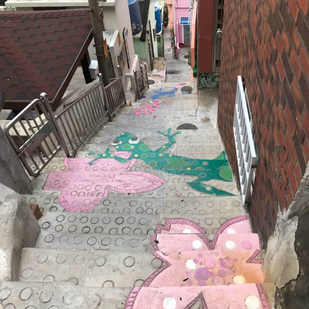 佐藤彩さんのインスタグラム写真 - (佐藤彩Instagram)「釜山のマチュピチュと言われている、甘川洞文化村✨﻿ 階段シリーズ✨ ここは斜面に沿って家が建てられていて、階段も見かけました。 歩いていると、こんなところにもカラフルに彩られた階段が！という発見もあって面白いです😊 しかも、とっても可愛らしい☺️ 思わず写真を撮りたくなるスポットですね。  ちなみに、天徳水の井戸には、昔、日照りが続き井戸が枯れてしまい、新たに井戸を掘ろうとして倒れてしまった青年の話があるのだとか。 急な斜面、水を運ぶのも確保するのも大変だったのでしょうね。  そして、住民たちが苦労して上り下りしたという、148段ある階段。 星を見に行く階段と名付けられているようです⭐︎ 上からも下からもデザインが楽しめるようになっていて、どちらからも見てみたい、と思う方も多いと思います。 けっこう急ですので、歩きやすい靴でお出かけすることをオススメします🌟  #釜山旅行  #甘川洞文化村  #階段カラフル #本の階段 #星を見に行く階段 #旅好き #HBC #アナウンサー #佐藤彩」5月31日 5時23分 - hbc_ayasato