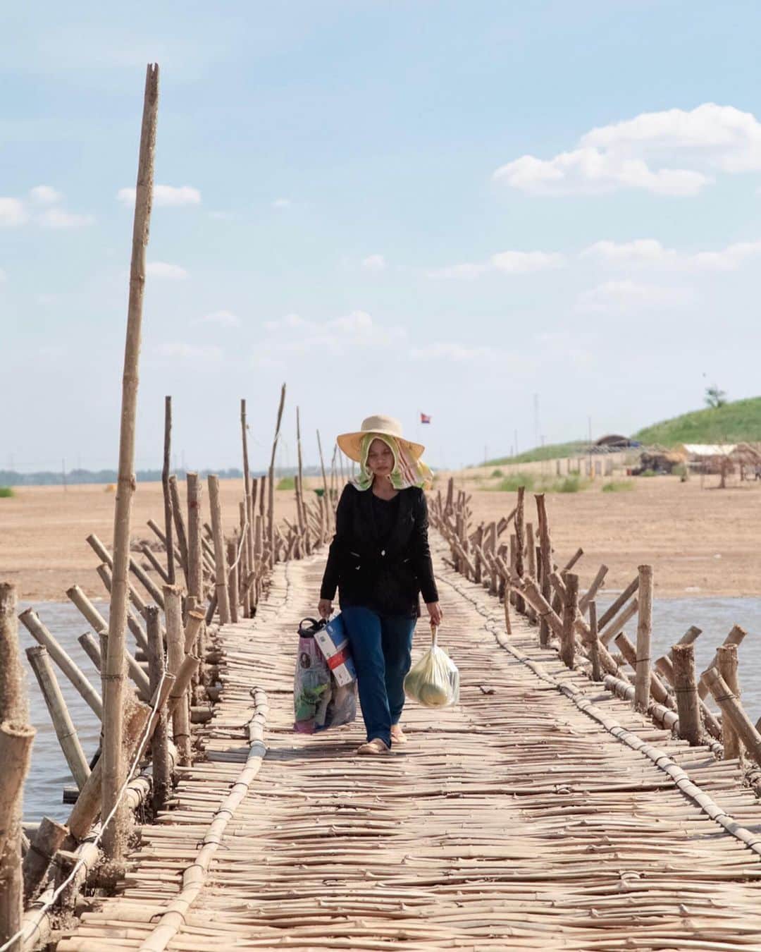 Shunsuke Miyatakeのインスタグラム：「A woman walking on Bamboo Bridge, Kampong Cham, Cambodia.  Each year, for decades, the island residents of Koh Paen built a seasonal, kilometre-long (1,000m) bamboo bridge for cars and pedestrians to cross the Mekong when the water levels were too low for a ferry. And each year, when the rains swelled the river, the elements would tear it down again.  Some says it's silly, but I love this story.」