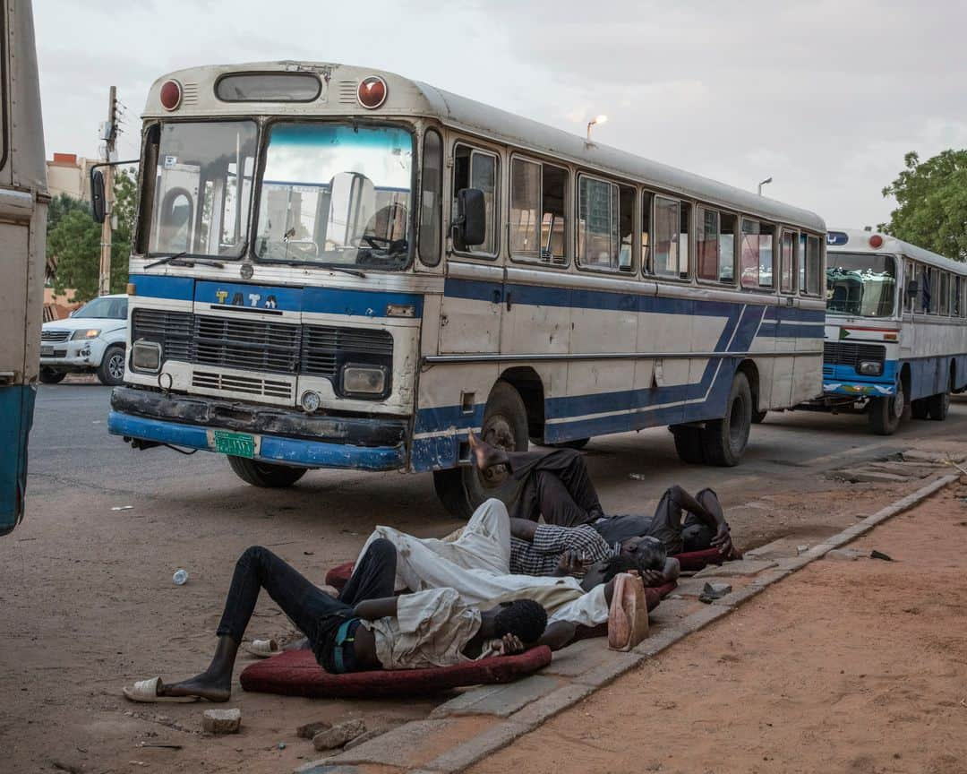 ルモンドさんのインスタグラム写真 - (ルモンドInstagram)「Khartoum 31 mai. Les ruraux qui envahissent les rues du centre sont là pour signifier une possible divergence du programme. Un test. Collectivement, ils ressemblent un peu au visage de la contre-révolution : on les a convoyés pour leur faire dire à quel point ils croient plus au pouvoir des militaires, à la prédominance du respect de l’islam qu’à toute autre considération présidant à l’organisation de la société soudanaise. Et qu’ils se contrefichent de la série de choses qui se discutent dans les rues de Khartoum nuit et jour, à moins de quinze minutes de marche.  Alors que géographiquement, tout se déroule dans un mouchoir de poche, on ne saurait être plus éloigné. Alors qu’au sit-in, festival de l’élan démocratique au Soudan, le débat et la fête continuent devant le quartier général de l’armée, un autre pays semble avoir envahi la rue pour un sit-in bis, mais express aux abords de l’avenue Al Qasr, l’avenue du palais, qui débouche effectivement à la présidence, ou plus exactement à l’entrée des deux présidences conjointes qui trônent le long du Nil : l’ancienne, toute blanche datant de la période coloniale, et l’autre, toute de marbre et de pierre sculptés, offerte par la Chine. >> L’actualité du continent africain est aussi sur notre compte @lemondeafrique<< - 1 et 2 : Après les deux jours de grève organisée par les dirigeants du mouvement civil de contestation, ceux ci continuent à occuper le sit-in aux abords du quartier général de l'armée. 31 mai.  3 et 4: En fin de journée, une manifestation en faveur du conseil des militaires a réuni plusieurs centaines de personnes amenées en bus au centre-ville.  Des slogans en faveur de la charia en vigueur étaient chantés et des portraits de Hemeti et de Abdel Fattah al-Burhane, les chefs du conseil militaire, étaient brandis.  Photo : @laurentvanderstockt #PourLeMonde — #Sudan #Uprising」6月1日 14時12分 - lemondefr