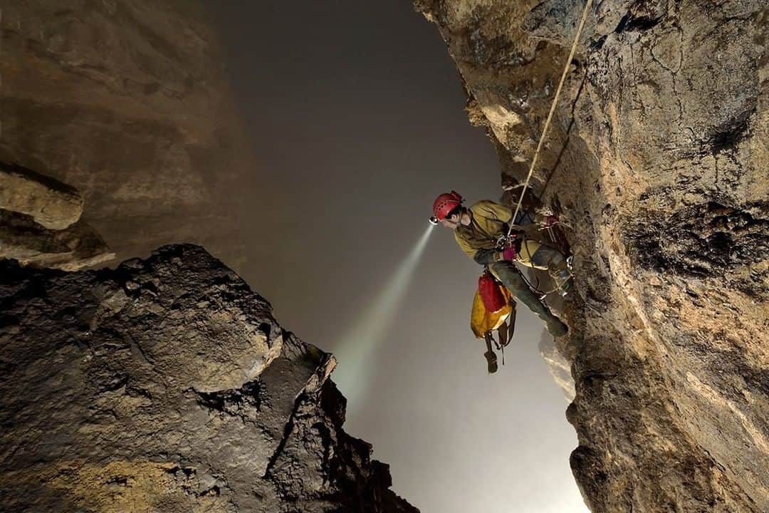 National Geographic Travelさんのインスタグラム写真 - (National Geographic TravelInstagram)「Photo by Robbie Shone @shonephoto | American speleologist and cave explorer Erin Lynch peers over her shoulder and down into the giant void of Cloud Ladder Hall. The fog gathers and remains trapped in the roof of this giant room and although the floor is out of view and can not be seen because of the cloud, her echo reminds her that it is over 300m (1000ft) below. This really is a very lofty location to be suspended from a single rope.」6月5日 10時07分 - natgeotravel