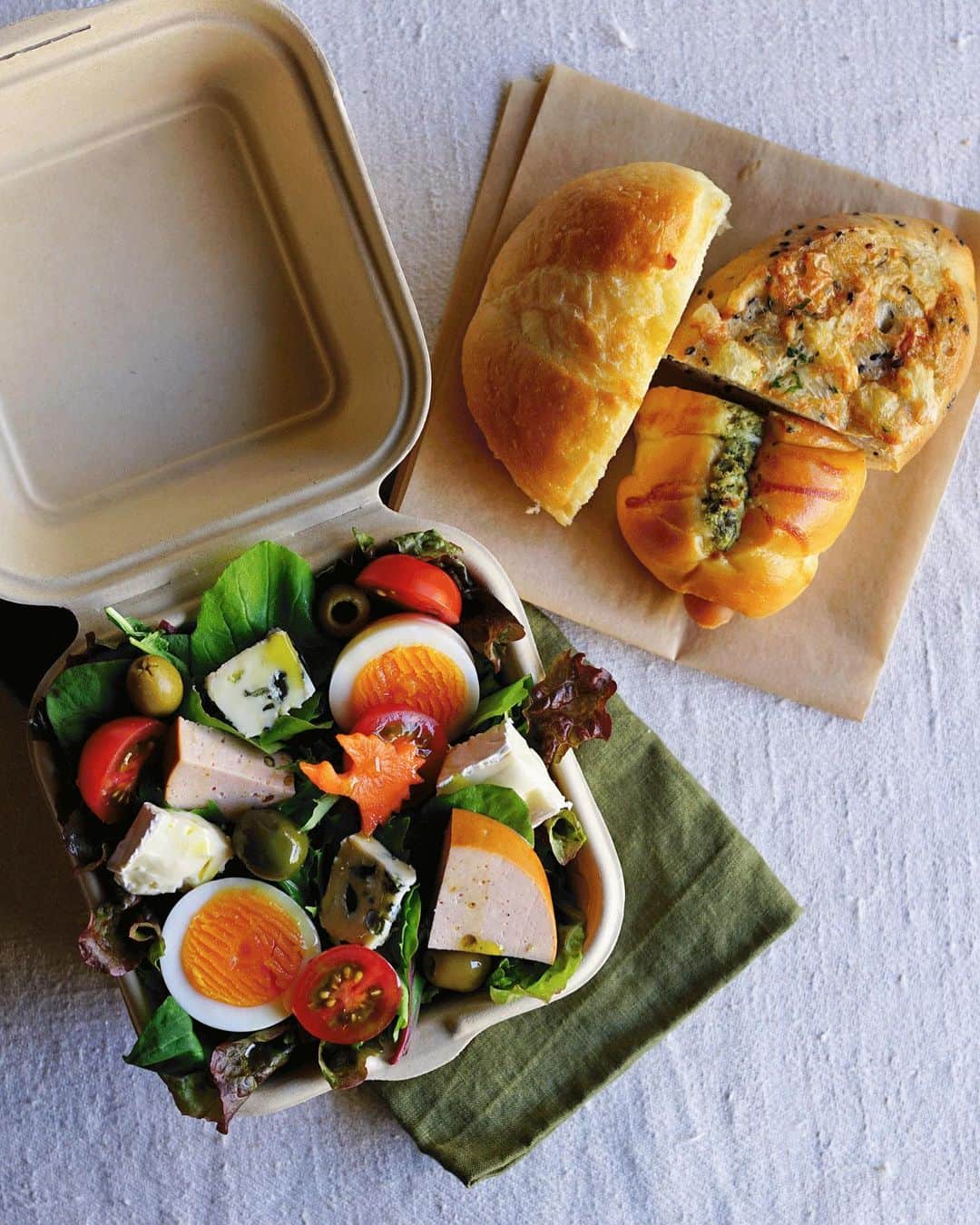 Ryoko Yunokiのインスタグラム：「+ + + Bread and salad bento/パンとサラダのお弁当 . *some bread *Green salad, topped with ham, hard-boiled egg, baby tomato, blue cheesem brie cheese and green olives, seasoned with salt/pepper and drizzled olive oil . *パン *グリーンサラダ。ハム、茹で卵、プチトマト、ブルーチーズ、ブリーチーズ、グリーンオリーブ。味付けは塩胡椒とオリーブオイル。 + + + #bento #お弁当 #丸の内弁当 #f52grams #紙パック弁当」