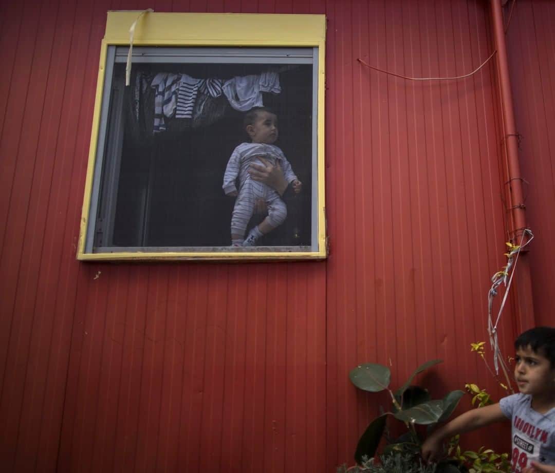 のインスタグラム：「Photo by Muhammed Muheisen @mmuheisen | Held by his mother, Ali, a seven-month-old Syrian refugee, looks out of the family’s shelter at a camp in Athens, Greece. For more photos and videos of the refugee crisis, follow me @mmuheisen @everydayrefugees and @mmuheisenpublic #everydayrefugees #muhammedmuheisen」