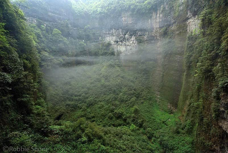 thephotosocietyさんのインスタグラム写真 - (thephotosocietyInstagram)「Photo by Robbie Shone @shonephoto | In a small clearing surrounded by trees and thick vegetation, three tiny explorers admire the scale of the Niubizi Tian Keng in Wulong, China. In such a space, the obvious question to ask by any cave explorer is how big the cave chamber must have been before the roof collapsed in opening it up to the daylight outside. Hidden from view, this lost world now contains it's own unique ecosystem thriving, secluded in paradise. Thin wisps of clouds gather and gently rise up following a heavy downpour of rain.」6月11日 21時28分 - thephotosociety