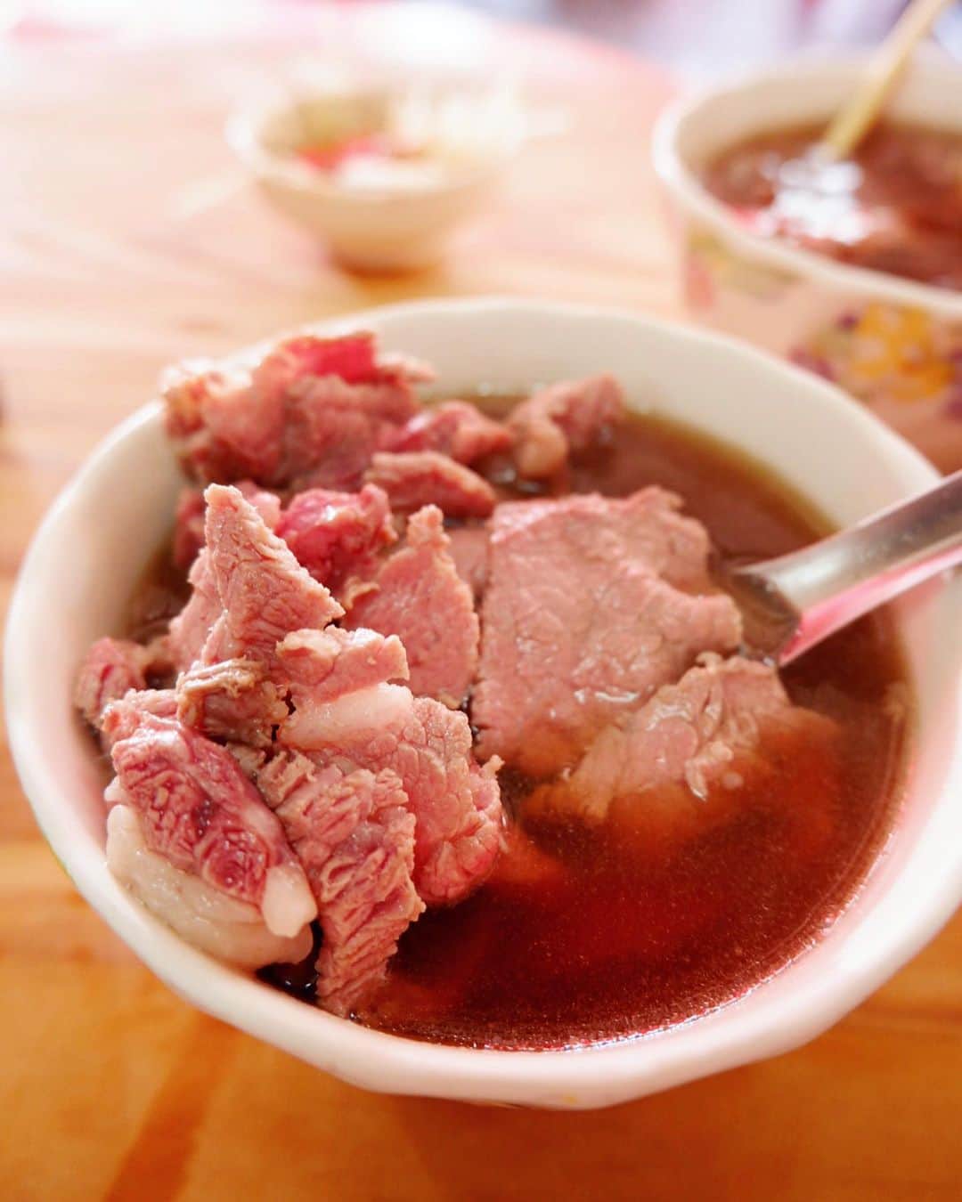 かおしさんのインスタグラム写真 - (かおしInstagram)「台湾日記続き🇹🇼 ・ 台南グルメのひとつ、#牛肉湯 (ギュウニクユと読みたいところだけどニュウロウタン😂)。 台南は牛肉の産地で、近くに食肉処理場もあるので、毎日新鮮な牛肉が手に入りやすいのだそう。 この牛肉湯は、生の牛肉に牛の骨や肉でダシをとった熱々のスープをかけて食べるシンプルな料理で、朝食としてよく食べられているらしい。 前々回、台南に来た時、牛肉湯の有名店#六千牛肉湯 に行ったら、たまたま休みだったので、リベンジとして前回行ってみたら、開いていて食べることができた😋 それが美味しくて、やっぱりまた食べたくて、今回も六千牛肉湯へ。 ・ こちらのお店は、オープンが朝5時😳 が‼️ 人気すぎて整理券(番号札)システムになっていて、早い人は4時とかに来て番号札を取っているらしい😳 番号札を持っている人たちは、オープンと同時に席に座れて、持ってない人たちはテーブルが空くのを待つシステム。 ・ 今回私たちは寝坊してしまい、行けたのは9時ごろ。 売り切れ次第終了なのでドキドキしながら向かったら…開いてたっ🙌 気温35℃、雲ひとつない晴天で、屋根もない場所で並びます🥵 前には12〜13人の人たちが並んでいて、予測として30〜40分かなといったところ。 並び始めて20分ほど経過し、汗だくで立っていたら、先に呼ばれた台湾人のご家族の若いお父さんが、私に傘を差し出してくれた😳⛱ 「自分たちは席に呼ばれたから、並んでいる間この傘を使えばいいよ。暑いから倒れちゃうよ💦」みたいなことを言って、笑顔で傘を渡してくれた(中国語でよくわからないけど、表情から多分そう)🥺 さらに、並んでいる場所に、車が近づいて来たらしいのだけれど、私は傘で全然後ろが見えてなくて気づかず。 そうしたら、後ろの若い台湾人カップルの男子が、私の肩をトントンして「そこは危ないよ。もう少し内側ににいた方がいいよ」(これまた中国語でわからないけど、多分そんな感じ)と笑顔で教えてくれた🥺 横で彼女もニコニコして、手で「もうちょっと内側に😉」みたいな仕草をしてくれた🥺 本当に優しい台湾の人たち✨ 台湾に来て、人の優しさに触れなかったことは、今までの旅で一度もない😭 本当に素敵な人たち✨🥺 ・ そうして待つこと10分ほど、やっと呼ばれたので、傘をお返しし、カウンターで牛肉湯を2つ注文。 台湾の人は、牛肉湯を白飯と食べることが多いそう。 私たちは今回朝ごはんをハシゴする予定があったので、店員さんに「ライス？」と聞かれたけど断ったよ🍚🙅 ‍そしてカウンターで生姜の千切りとタレ(甘め)を小皿に取り、席で待っていると、しばらくして牛肉湯が運ばれてきて、席でお支払い。 1杯120元(約420円)。 ほんのり赤味を帯びて半生の状態で食べる牛肉は、割と歯ごたえがあって食べ応えがあるし、スープも優しい美味しさ。 お肉はタレにつけて生姜と一緒に食べても美味しい(なるほど、ご飯に合いそう💡)。 ペロリと完食😋 お肉チャージで元気満タン‼️ 決して派手な料理ではないけれど、また食べたくなるんだよね😊 ・ #かおし旅 #かおし台南旅行 #台湾 #taiwan #旅グルメ #tainan #台湾グルメ #台湾旅行 #グルメ好きな人と繋がりたい #旅好きな人と繋がりたい #旅行好きな人と繋がりたい #igersjp #retrip_taiwan #retrip_gourmet #jalan_travel #jtbで旅したい #tabicoorde #repostrurubu #rurubu1st #チェジュ島行きたい #imatabiキャンペーン7 #今だからできる旅 #photo_shorttrip #タビジョ #台湾好きな人と繋がりたい」6月16日 23時47分 - cao_life