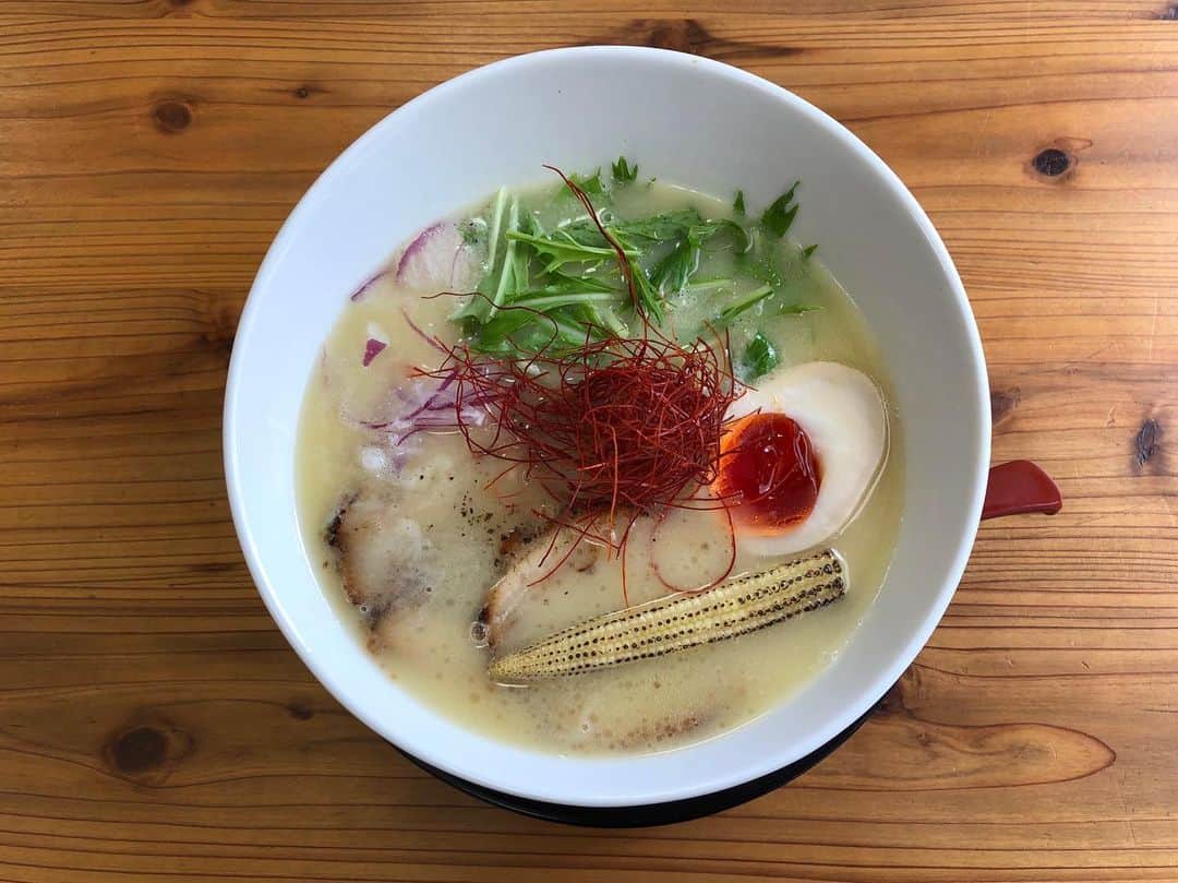 のインスタグラム：「大阪ラーメン探訪① 大阪浪速区元町YOLOpeeps 濃厚鶏白湯ラーメン  味が濃そうでどこか他所の国のスープにも見えてしまうビジュアルだが、国産鶏ガラ、モミジ、野菜を長時間煮込んだスープにカエシは昆布とホタテを使った塩ダレを使用。コラーゲン豊富なモミジから自然なトロみが出、他の材料は奥深いコクを感じさせながらもスッキリとしている輪郭を作り上げている。イタリア産のブランド豚、ドルチェポルコのバラ肉のチャーシューもトロトロで見事にスープにマッチ。特筆すべきは枚方市にあるミネヤ食品で作られたという中太麺とスープの絡み方が最高である事。このスープのためにこの麺が作られたのでは？と思うほどでこの疑問を解決すべく質問したところ、ミネヤさんにスープを飲んでもらい改良を重ねて現在の小麦の配合、麺の太さになったとの事。やはり！と思える答えが返ってきた。上に乗っている具材は大分県産の天然飼料で育てられた蘭王卵の味玉、ヤングコーン、赤タマネギ、水菜、糸とうがらし。彩だけで乗せられた具材にも見えるが全てに意味があり絶妙。赤タマネギ(アーリーレッド)は麺を啜る合間に食すと甘みを含んだ水々しさが舌の新鮮さ取り戻してくれ、水菜とヤングコーンのシャキシャキやコリコリが麺との食感の差を楽しませてくれる。糸とうがらしは辛味よりも旨味が強く、少しずつスープに浸していくとグラデーションをかけたようにスープの深みを変化させていく。この深みの変化のさせ方は初めて。スゴい。  ①Overall picture of ramen(全体像) ②Shop front(店構え) ③Soup like a waterfall.The thick soup is shining beautifully.  It's like slow motion.(スープを滝のようにする。トロみのあるスープが美しく輝いている。スローモーションのようだ) ④Lift noodles.Take the beautiful girl in a red dress.(麺を持ち上げる。赤いドレスの美女を連れて) ⑤roasted pork fillet.  It's too soft and I can't hold it with chopsticks.(チャーシュー。柔らかすぎてお箸で持てない) ⑥roasted pork fillet. Visual confirmation of the feeling of movement.Delicate girl who got on chinese soup spoon.(チャーシュー。躍動感を確認。れんげに乗った繊細な彼女)  #yolopeeps #大阪ラーメン #ラーメン #らーめん #拉麺 #ramen #麺 #ramennoodles #instaramen #instafood」