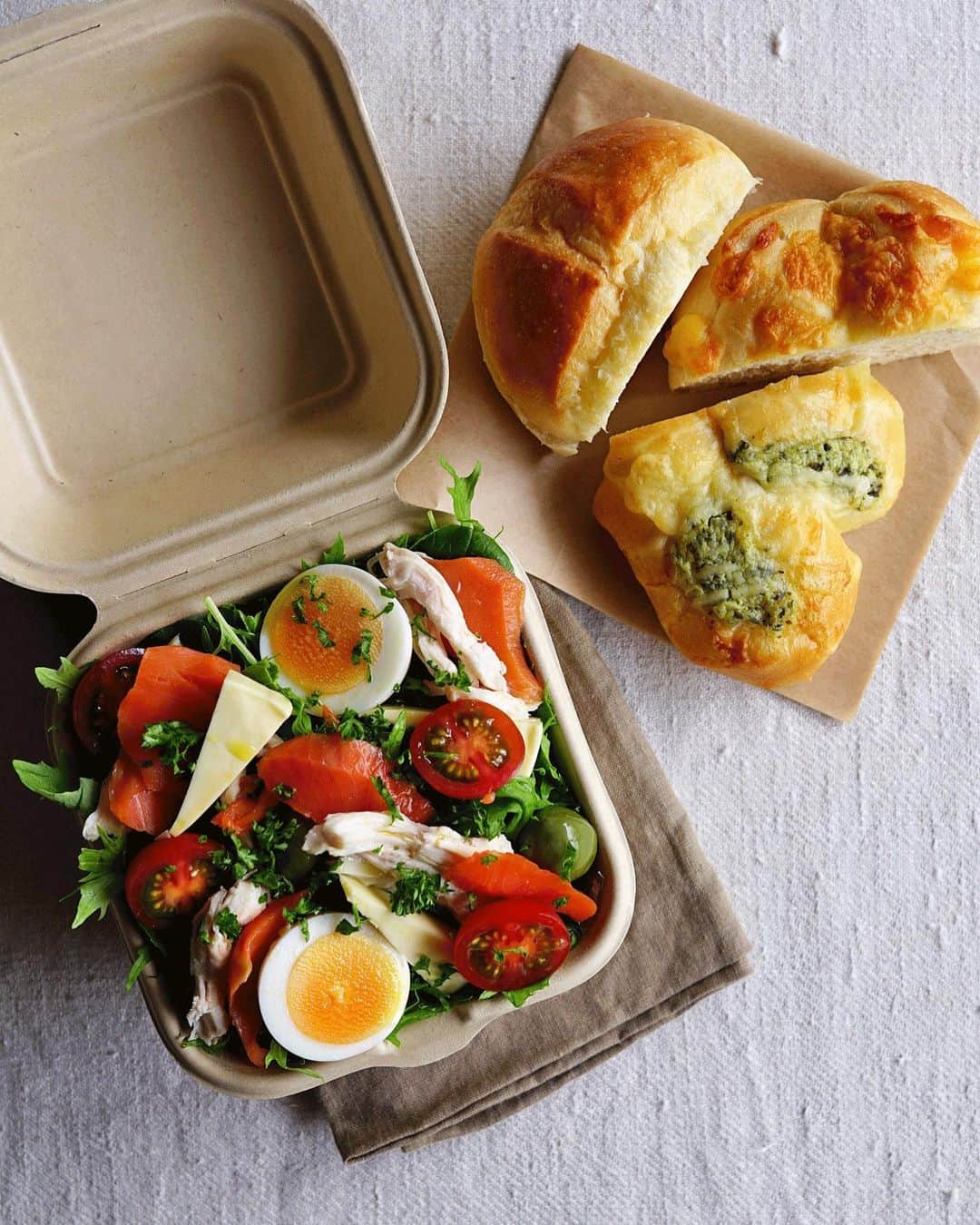 Ryoko Yunokiのインスタグラム：「+ + + Bread and salad bento/パンとサラダのお弁当 . *some bread *Green salad, topped with poached chicken, smoked salmon, hard-boiled egg, baby tomato, cheese and green olives, seasoned with salt/pepper and drizzled olive oil . *パン *グリーンサラダ。茹で鶏、スモークサーモン、茹で卵、プチトマト、チーズ、グリーンオリーブ。味付けは塩胡椒とオリーブオイル。 + + + #bento #お弁当 #丸の内弁当 #f52grams #紙パック弁当」