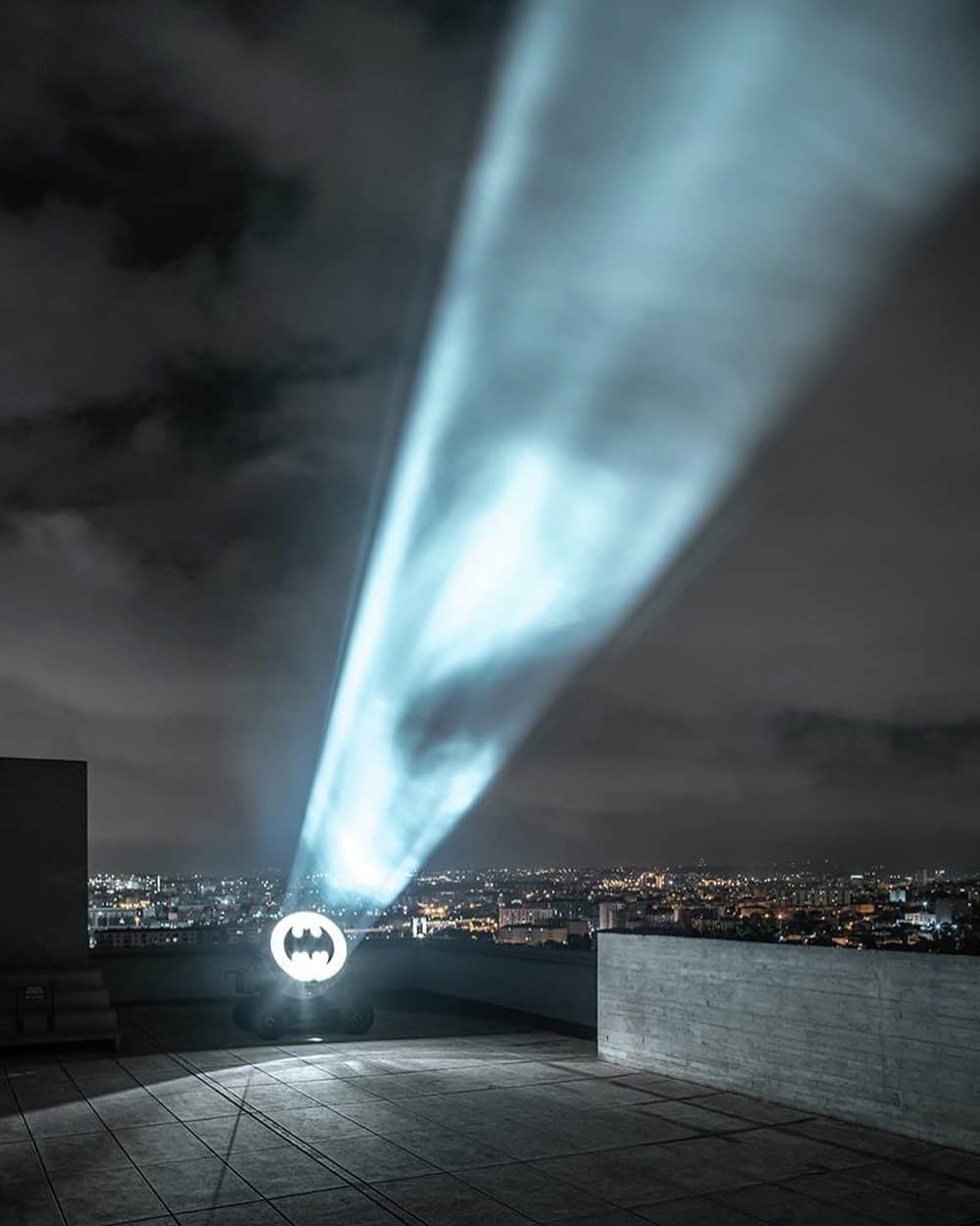 のインスタグラム：「"Alex Israel" currently occupies the rooftop deck and former gymnasium of Le Corbusier’s iconic Cité Radieuse at MAMO. Inspired by Marseille’s gritty history and the architect’s use of concrete, Israel has reimagined the rooftop as Gotham City.  Continuing the artist’s ongoing exploration of rented film props as readymade sculpture, the Batmobile serves as the exhibition's centerpiece with smoke, light, and sound, while the Bat-Signal, projected high above the city, activates the night sky throughout the summer. Learn more via the link in our bio. __________ #AlexIsrael #MAMO #Gagosian @alexisrael @marseillemodulor Installation view, "Alex Israel," MAMO–Marseille Modulor, France, June 8–August 31, 2019. Artwork © Alex Israel」