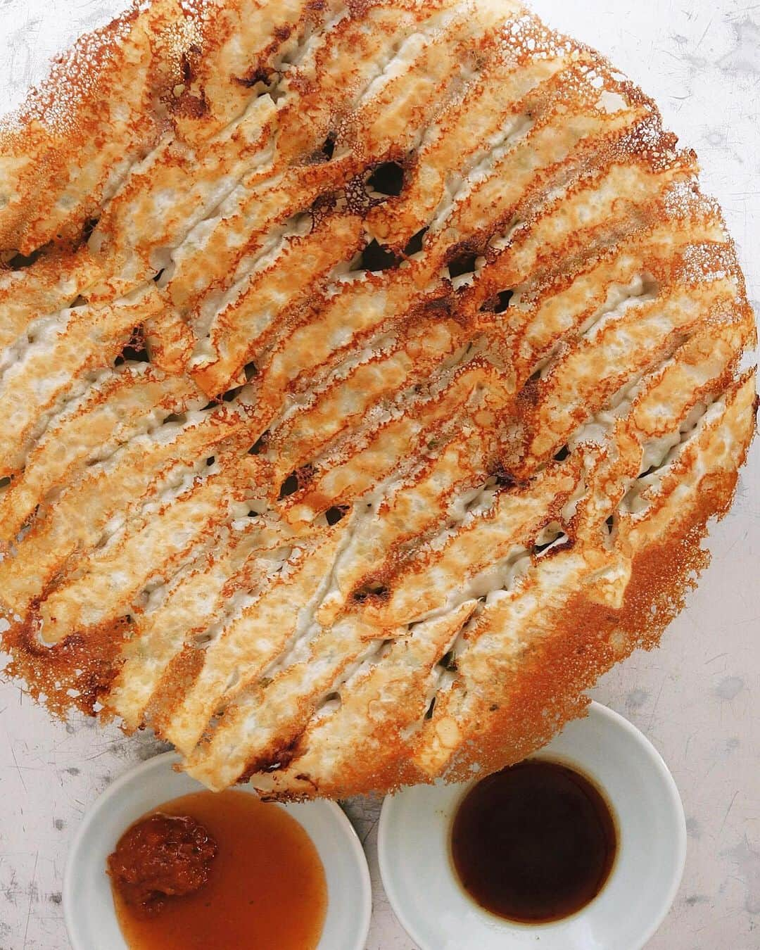 樋口正樹さんのインスタグラム写真 - (樋口正樹Instagram)「Gyoza . 日曜の夜に焼き餃子。 具は豚肉＆キャベツ、 薄皮使いヒダ無しで。 ヒダ無しって簡単で、 口当たり良いのです。 餃子を焼いてるとき 肉汁が少し漏れると 焼き上がりのフチが チリチリになり美味。 . タレは２種用意して ラブパクとヤミパク。 交互で食べるのが◎。 . . #餃子 #ぎょうざ #ラブパク食堂#ラブパクチーソース #ヤミーザパクチー #パクチー醤油 #gyoza #frieddumplings #lovepakcheesauce #yummythephakchi #crispybottoms」6月30日 19時49分 - higuccini