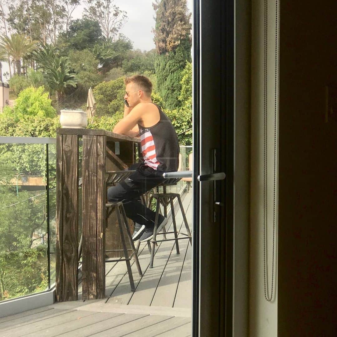 グレン・パウエルのインスタグラム：「On July 3, 2018, one year ago today, I found out I was NOT going to be in “Top Gun: Maverick”... This is a picture of me getting that call.  Even though I’m the most patriotic person most folks have ever met (as you can see I was wearing an American flag tank top and aviators at home cause, you know, it was a Monday). And even though Fourth of July is my favorite holiday, I spent it last year in the fetal position. Far away from roman candles, a grill, and barely able to whisper the words ‘freedom’ without crying.  Here we are one year later and I’ve just wrapped the greatest movie you can’t see yet. A movie that I’ve wanted to make since I was a kid alongside the man I’ve modeled my career after. And even more I’ve gotten to work every day with the brave men and women of the United States Navy who ensure our freedom here and abroad. I love America, and I can’t wait to celebrate her properly this year…  Also, if you run into @tomcruise today, tell him Happy Birthday. #topgunmaverick」