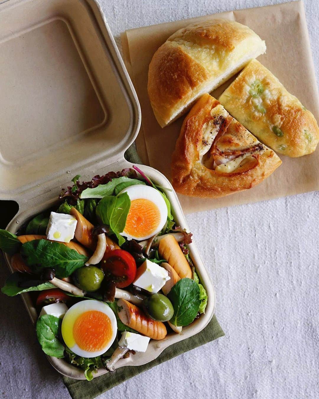 Ryoko Yunokiのインスタグラム：「+ + + Bread and salad bento/パンとサラダのお弁当 . *some bread *Green salad, topped with stir-fried sausage and mushroom, hard-boiled egg, baby tomato, kiri cheese and green olives, seasoned with salt/pepper and drizzled olive oil . *パン *グリーンサラダ。ソーセージとシメジの炒め物、茹で卵、プチトマト、クリームチーズ、グリーンオリーブ。味付けは塩胡椒とオリーブオイル。 + + + #bento #お弁当 #丸の内弁当 #f52grams #紙パック弁当」