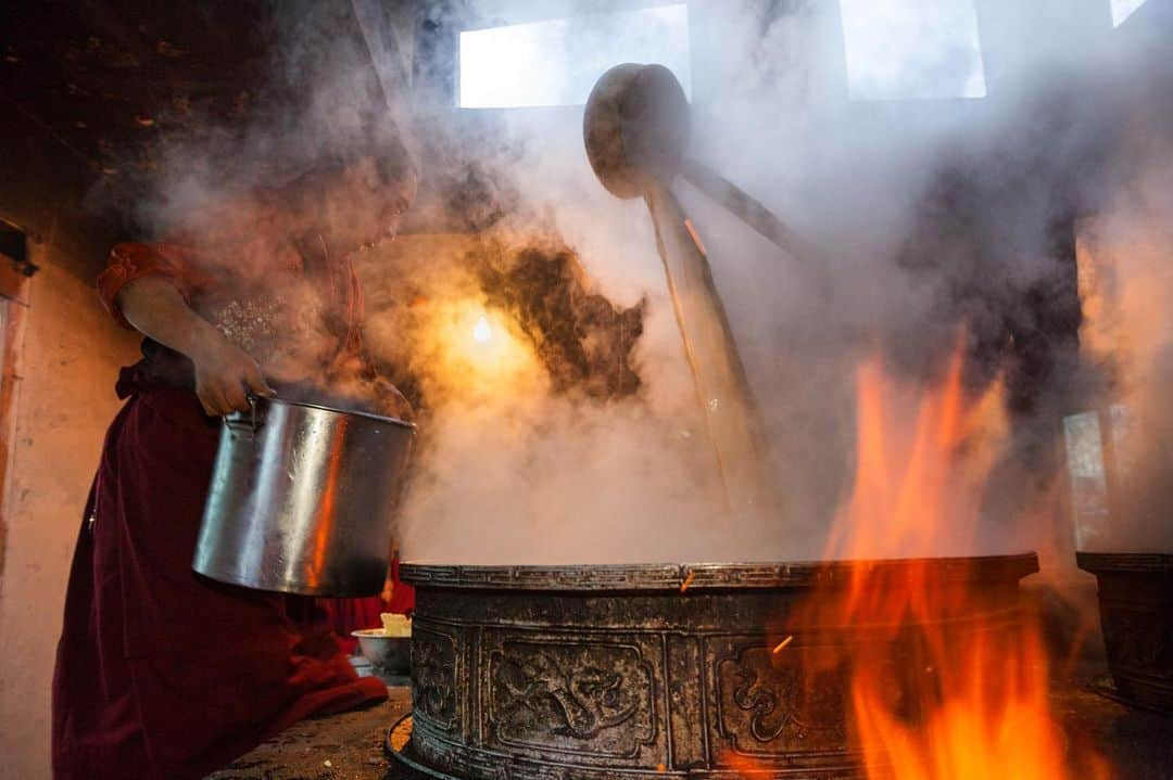 Michael Yamashitaさんのインスタグラム写真 - (Michael YamashitaInstagram)「Steam and smoke, hide then reveal, two monks making yak butter tea for 400 of their brethren at Shechen Monastery. Yak butter tea is a mix of yak butter, salt, and a thick tea broth made from boiling both leaves and stems. It is highly caloric, good for energy for long prayer sessions in the cold. Situated along the Tea Horse Road, in the eastern Tibetan region of Kham, this and many other my photos will be on exhibit during the Songtsam Cultural Week at the Modern Art Academy in Shanghai. The exhibit opens this weekend. #Sichuan #buttertea #teahorseroad #ZiWu #photoexhibition @songtsam」7月12日 5時05分 - yamashitaphoto