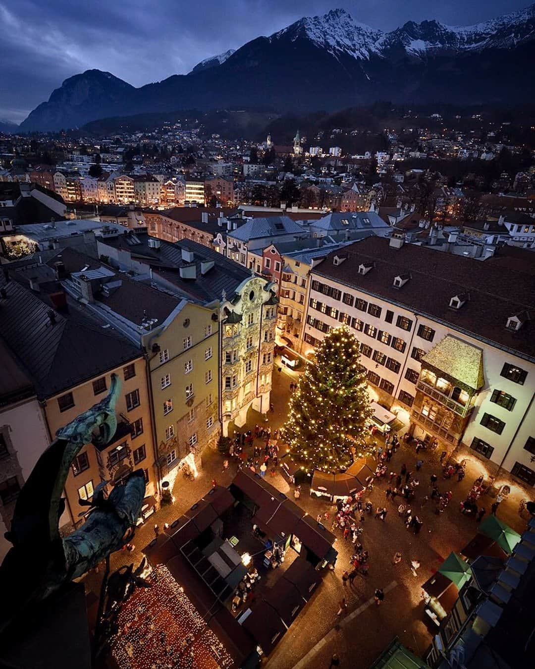 National Geographic Travelのインスタグラム：「Photo by Robbie Shone @shonephoto | Festive shoppers enjoy the Christmas markets in the Old Town of Innsbruck, Austria, set against the Alps. Next to the giant trimmed tree is the Golden Roof, a landmark structure built in 1500 for Emperor Maximilian I.」