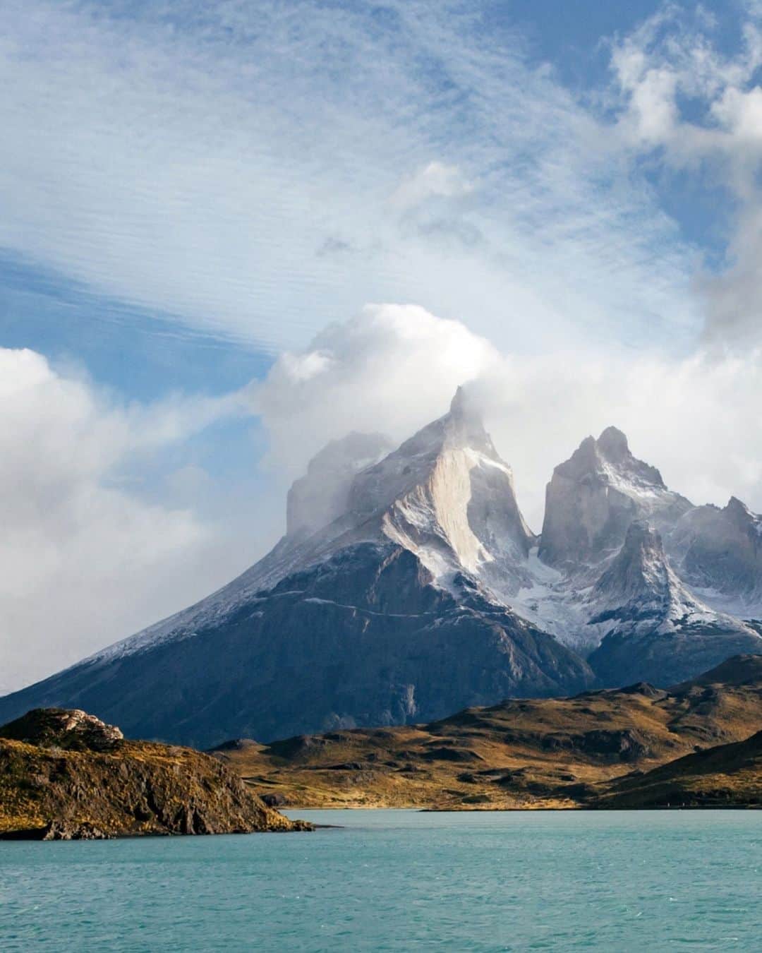 National Geographic Travelのインスタグラム：「Photos by @michaelgeorge | Chilean Patagonia’s Torres del Paine is the rare park where humans are true outsiders in a vast, legitimate wilderness. Though it occupies 930 square miles (2,400 sq km), the park received only 140,000 visitors throughout 2022. Compare that with Zion National Park, where last year close to 4.7 million people explored its 232-square-mile (600-sq-km) expanse.  This image was captured as I traveled over Lago Pehoé, which translates to “hidden lake.” The brilliant color is caused by glacial flour, or rock dust suspended in the water. Prior to visiting Torres del Paine, I presumed all photos I’d seen of it had the saturation turned up to exaggerate the colors. I was pleasantly surprised that this is not so—those colors are precisely how they look. It’s as if all the natural features that make a landscape beautiful are turned up a notch. In the distance you can see Macizo Paine, a group of mountains that look like broken teeth.」