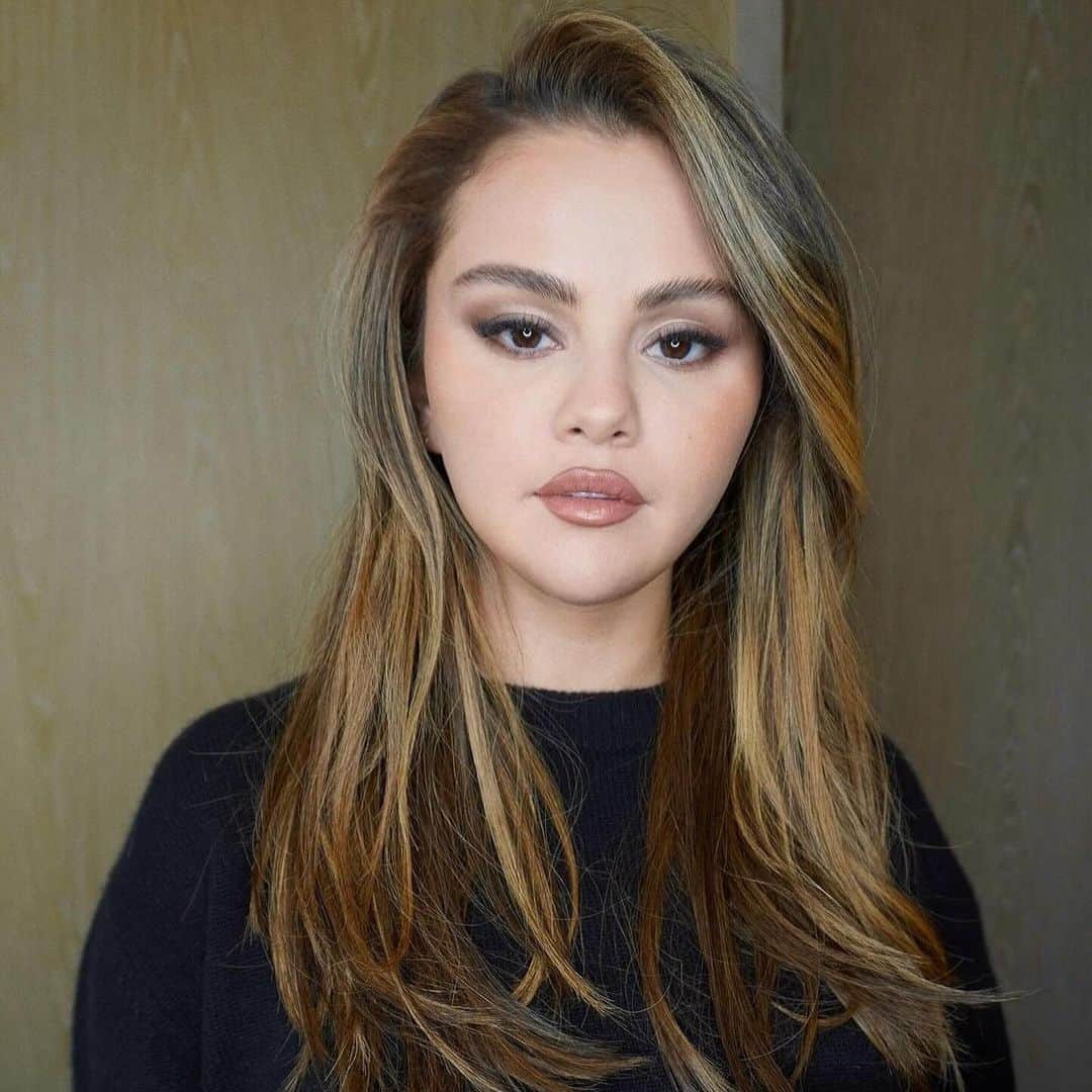 Vogue Beautyのインスタグラム：「She may be a faithful brunette, but @selenagomez still knows precisely how to shake up her hair look. The star debuted sun-kissed "babylights" through her mocha mid-length cut, with a seasonally appropriate smoky eye and festive red manicure, but excellent color like this is for life, not just for Christmas. At the link in our bio, find all the details on her masterclass on illuminating the face without straying from your natural brunette.」