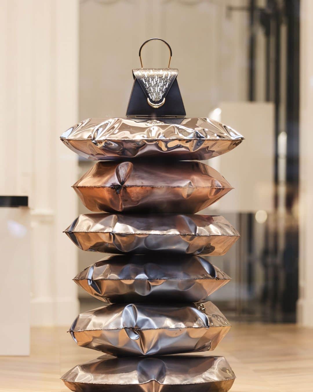 デルボーのインスタグラム：「Catch the light. ⁣ ⁣ Celebrate the feeling of magic and surprise in our flagship boutiques. Belgian artist Ben Storms designed Delvaux’s holiday window installations - sculptural stainless steel pillows arranged in a tower atop which rest some of the most exceptional designs from our collections, including the Caprice Firework.⁣ ⁣ #Delvaux」