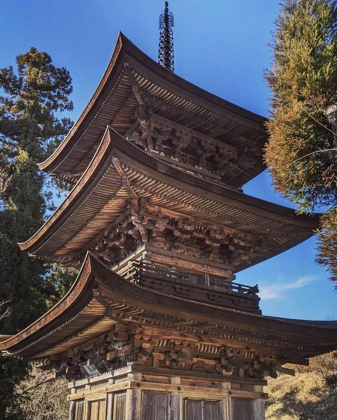 ?長野県 観光 公式インスタグラム のインスタグラム：「// Photo by @naoyuki.kobayashi.3  国宝 「大法寺 三重塔」 ＠青木村  和様の建築様式が正確に守られ建てられた  「大法寺 三重塔」   空を舞う鳥の羽のように広がる三層の屋根と、どっしりとした塔全体のバランスが崇高な印象を与えます😊✨️  建築物としてはもちろん、周囲の景観や風光との調和も美しく国宝に指定されています👀✨️  その美しさから、近くを通る旅人が ふり返りふり返り塔を眺めたことから「見返りの塔」とも呼ばれていますよ😀✨️  ＝＝＝＝＝＝＝＝＝  The Three-Story Pagoda of Daihouji Temple (Aoki Village)  The three-story pagoda of Daihouji Temple is a precise expression of Japanese-style architecture.  The balance of the sturdy pagoda tower and the three tiered rooves, which curve outward elegantly like a bird’s wings, is sublime.  Beyond the structure itself, the pagoda also harmonizes beautiful with the surrounding landscape and nature, earning it a place as one of Japan’s national treasures.  Due to its beauty, visitors couldn’t help but look back at the pagoda as they left, earning it the nickname, “Mikaeri-no-to.”  ＿＿＿＿＿＿＿＿＿　  Location / Aoki Village , Nagano , Japan   #おうちでながの #長野のいいところ #大法寺 #青木村  ＿＿＿＿＿＿＿＿＿  🍁インスタアワード秋冬⛄作品募集中📷  #長野の列車旅秋冬 撮影場所(長野県内に限ります) をキャプションに入れて 応募期間（10/16～1/31）に投稿してください。 優秀作品に選ばれると 長野県特産品セットをプレゼント🎁」