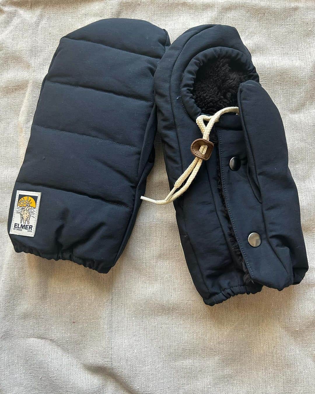 LEEのインスタグラム：「『Elmer by Swany （エルマーバイスワニー）』のミトン。LEE編集部のお買い物  昨年の冬、『Elmer by Swany （エルマーバイスワニー）』の鮮やかなブルーのミトンを身につけている人がいて、なんて可愛い手袋！欲しい！と思っていたのですが、そのときは買えませんでした。時は経ち、猛暑の夏を過ごしすっかり忘れていたのですが、また寒くなってきてものすごく欲しかった手袋があった！と思い出し、ようやく購入しました。  迷いに迷ってネイビーに。 こちらのミトン、オレンジやブラウンやブルーなど他のカラーも可愛い上、もこもこのボアのタイプなど同じブランドの他の手袋も魅力的。…悩んだ末、ネイビーにしました。（ボアの手袋、今見ても本当に可愛い）  「エルマーバイスワニー」について調べると…。 ニューヨーク州北部にある「手袋屋の町」と呼ばれるグラバーズビルで、手袋職人のエルマー・リトルが1893 年に創立した「エルマー リトル & サンズ」。 そして、日本の手袋の産地として知られる、香川県東かがわ市（旧白鳥町）の⽼舗手袋メーカー「SWANY（スワニー）」。 『Elmer by Swany（エルマーバイスワニー）』は、エルマー・リトルの職人技や職人魂を引き継ぐように、SWANY（スワニー）が手掛けるブランド。手袋を丁寧につくってきた人々の気持ちがこもっているように思えます。  デザインにも惚れました！ 手の甲側はふっくらマットな質感。手の平側は、指が出せるホールとスナップボタンがある細やかなディテール。ホールを調整できる紐もついていて、キュッとホールを小さくできます。自転車移動多めなので、冬の相棒に。S子  #エルマーバイスワニー #ElmerbySwany  #ミトン #手袋 #あったか小物 #LEE編集部のお買い物 #magazinelee」