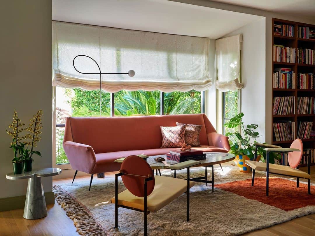 ELLE DECORのインスタグラム：「“So much of my practice utilizes color, high-contrast texture—and a lot of optimism,” says ELLE DECOR A-List designer Oliver Furth (@olivermfurth). “Smart, sophisticated people are catching on that color can be luxurious and joyful.” The designer recently found his kindred spirits in a Los Angeles couple who wanted the interiors of their residence to feel welcoming, unpretentious, and—yes—include plenty of color. Furth used virtually every crayon in his box. Here in the library, a vintage salmon-pink Carlo de Carli settee is accompanied by a pair of tangerine @mmariomilana lounge chairs. The handwoven Moroccan rug by @beni_rugs helps warm up the space.  To step inside this color-drenched dream home, as toured exclusively on elledecor.com, click the link in bio. Written by @davidbryannash. Photographed by @rogerdaviesphotography.」