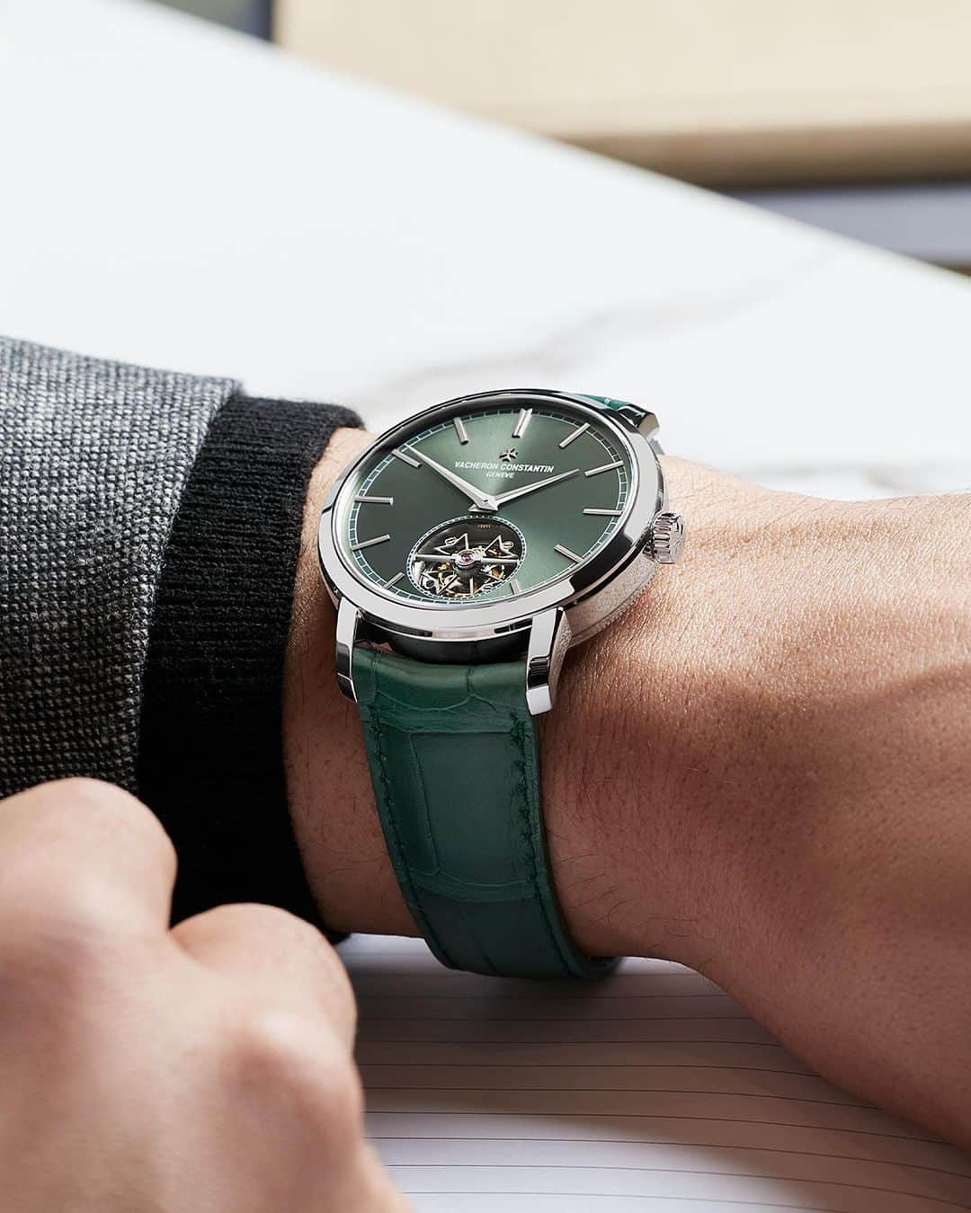 ヴァシュロン コンスタンタンのインスタグラム：「Raise your hand if you like tourbillon ✋  The Traditionnelle tourbillon watch appearing in a 41 mm-diameter platinum case features a majestic sunburst green dial.  🤏 The intrinsic elegance of this new Traditionnelle tourbillon also stems from the slenderness of the case, itself enabled by ultra-thin self-winding in-house Calibre 2160/1 measuring only 5.65 mm thick.   This thinness is the result of perfect technical mastery, especially since this calibre incorporates a tourbillon regulator mechanism designed to compensate for the effects of gravity on the isochronism of the balance-spring.  ⚡To clearly understand how it operates, this regulator has been set to a frequency of 18,000 vibrations per hour (2.5 Hz). This relatively slow tempo often found in historical pocket watches provides an opportunity to appreciate at leisure the tourbillon’s mechanical ballet.   🔎 The show that can be admired through the sapphire crystal caseback is enhanced by the movement’s structure incorporating a peripheral rotor. The latter reduces the thickness of the calibre as well as ensuring a comfortable 80-hour power reserve.  #VacheronConstantin #OneOfNotMany #vacheron #thehourlounge #watches #watch #watchesofinstagram #horology #watchoftheday #instawatch」