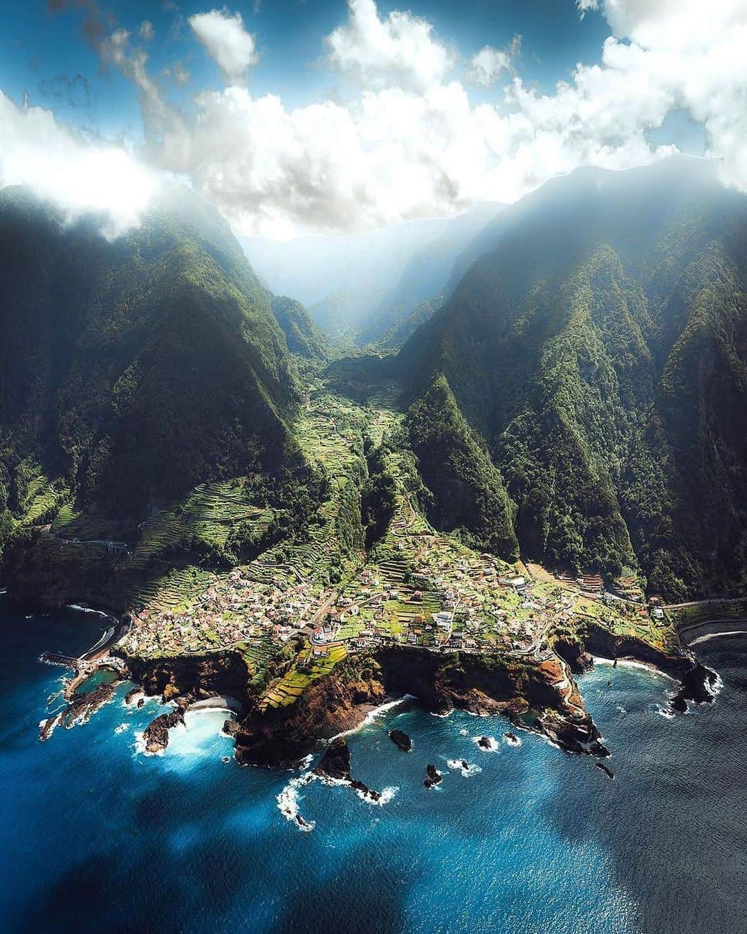 Coronaのインスタグラム：「Within the green peaks of Madeira lies the quaint village of Seixal. As beautiful as it looks from a distance, the area boasts several options for those seeking adventure beyond the town.   For those wanting to try their hand at hiking, head to Miradouro do Veu da Noiva which fittingly translates to ‘The Bridal Veil Waterfall’. This impressive waterfall cascades over 110M high and into the ocean with stunning views of the coast once you reach the top.   If you travel further south, you’ll come across Chão da Ribeira valley. A short hike of just 10km brings you to the laurislva forest, where you’ll find more stunning waterfalls on the way and incredible views of Madeira.  #ThisIsLiving   📷: @ilya.somewhere   #Portugal」