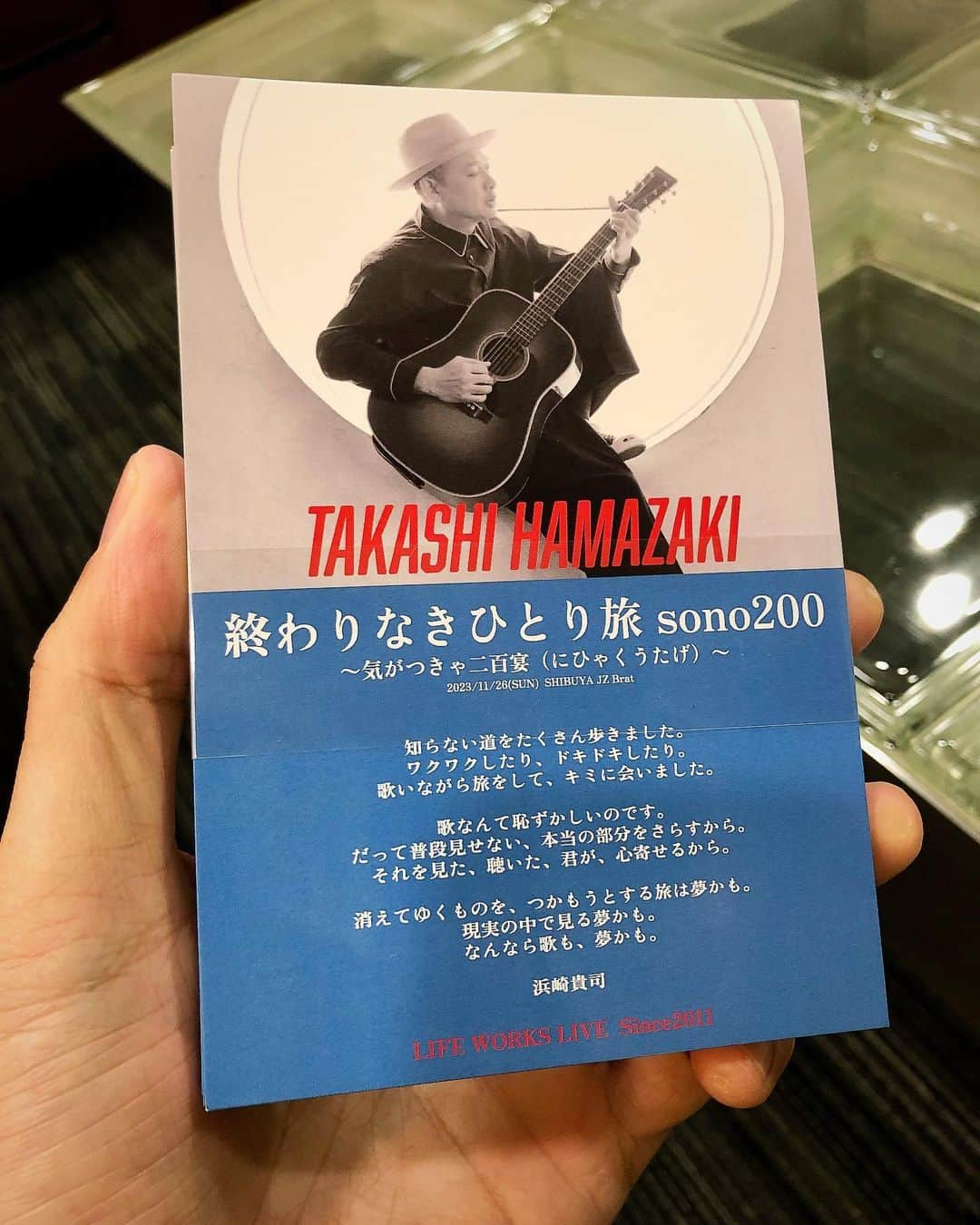 浜崎貴司さんのインスタグラム写真 - (浜崎貴司Instagram)「いよいよ明日、弾き語りツアー200回目の渋谷公演です。  200回公演の中で最大の事件と言えば、  やはり私が京都で、中年男性に下着を盗まれた事件でしょうね・・。  それについては何度も話しましたが、  改めて明日また・・。  いや、もういいか・・。  もうひとつ記憶に残っているのは、  2014年の夏に青森、秋田、宮城、山形、福島を回った時のことですね。  スケジュールは以下でした。  8/16青森、8/17秋田、8/18移動日、8/19仙台、8/20山形、8/21移動日、8/22いわき。  7日間で5公演というハードスケジュールでした。  当時私は49歳。  弾き語りツアーも始まって3年目でしたので、無我夢中でした。  で、東北シリーズの最終日、福島県いわき市でのライブの際、  声がちゃんと出なくなってしまったのです。  歌と、タバコと、連日の酒で、声帯が炎症を起こしてしまったのでした。  その後東京に戻り病院で検査したら、  お医者さんに、  「今後プロとして唄い続けるのなら、タバコはやめたほうがいい」と言われました。  で、その日からタバコをやめたのです。  なぜか簡単にやめられました。  やめて数年はちょっと歌や創作に違和感がありましたが、  今ではまったく問題を感じません。  それ以降、アディクションと呼ばれる「嗜癖(しへき)」について考えるようになりました。  嗜癖とは、有害と分かりつつも続けてしまう脳障害のことで、  簡単に言えば様々な依存症のとこです。  最近では、毎日飲んでいた酒もコントロールしてみると、  こちらも意思で飲まない日がつくれるようになりました。  今では1週間くらいは普通に飲まずに過ごすことが出来ます。  コーヒーは相変わらず飲みますが、  ノンカフェインにしてみたり、  麦茶に変えてみたりしていたら、  量を減らすことが出来ました。  ただ何かを減らすと別のものが増えたりします。  タバコをやめたらお菓子が前より好きになりました。  次は砂糖の嗜癖。  脳は常にハマるものを探しています。  最近話題になっているホスト通いの女性達の一件も、  そんな嗜癖のひとつかもしれません。  人はなぜか羽目を外したがります。  日常からずれた夢を見たがっています。  私の嗜癖から逃れようとする行為は、  夢から正気に戻す作業に近いのですが、  私の日常はどこか夢みたいなものなので、  逆に正気を保たないと、  身が持たないということかもしれません。  そう、旅先で男に下着を盗まれる人生ですから・・。  写真は昨日出来上がった弾き語りツアー200公演記念のポストカード。  明日来場者の皆さんにプレゼントします！  浜崎貴司 弾き語りツアー "LIFE WORKS LIVE ～ Since2011/終わりなきひとり旅” sono200　〜気がつきゃ二百宴（にひゃくうたげ）〜  supported by CLOSET PARTY  ★スペシャルゲスト 近藤康平（LIVE PAINTING）  ■日程： 2023年11月 26日（日）  ■会場： 東京　渋谷JZ Brat  ■時間： 開場17:00　開演18:00  チケット発売中  #終わりなきひとり旅  #嗜癖  #アディクション  #addiction」11月25日 8時40分 - hamazakitakashi_official