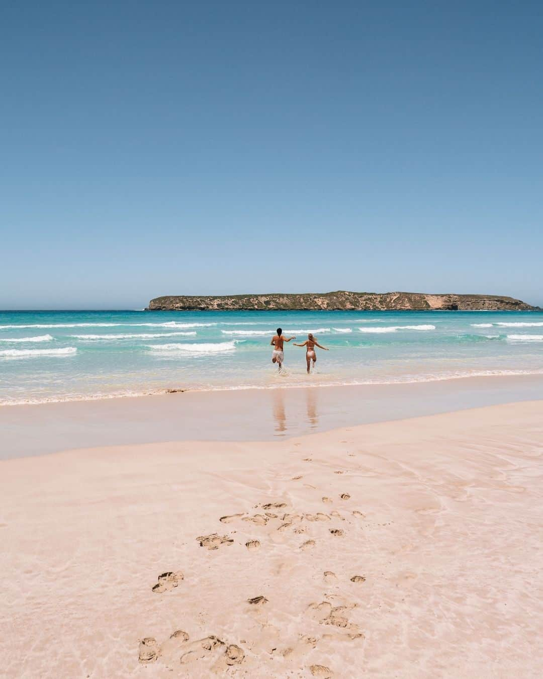 Australiaさんのインスタグラム写真 - (AustraliaInstagram)「Race you to #CoffinBay?! 🏁🏃 You'll find this splendid stretch of coastline in @southaustralia's vibrant @eyrepeninsula, a region home to uber-fresh seafood, unique wildlife and white sand beaches just like this ☝️ Dive into the clear blue water, then treat your taste buds to a feast of oysters plucked straight from the ocean at @coffinbayoysterfarmtours, or head to nearby #PortLincoln and join @calypsostarcharters to swim with local #SeaLions, aka the playful puppies of the sea 🦪🤿  #SeeAustralia #ComeAndSayGday #SeeSouthAustralia #EyrePeninsula  ID: Two individuals joyfully sprint towards the glistening ocean at Almonta Beach in Coffin Bay National Park, South Australia. Their footprints are imprinted on the smooth sand, contrasting against the vibrant backdrop of a clear sky and a rocky island in the distance.」11月26日 4時00分 - australia