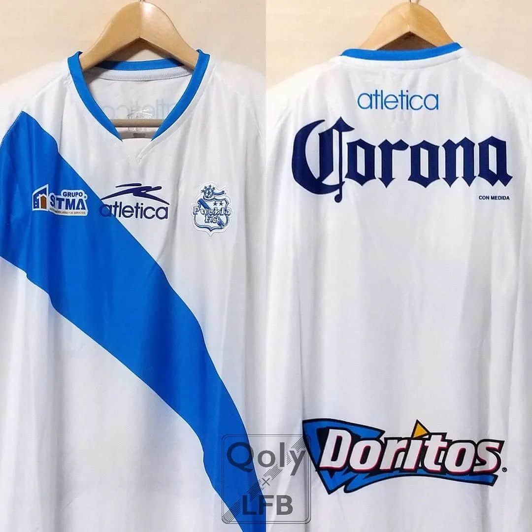 サッカーニュース：Qoly（コリー）のインスタグラム：「プエブラ 2007-08 Atletica ホーム半袖 ユニフォーム  #メキシコリーグ 、 #プエブラFC の2007-08シーズンの #ホームユニフォーム 。  クラブ創設は1944年でホームタウンはプエブラ州の州都プエブラ。 ユニフォームデザインは白地に青のタスキがけが伝統のスタイル。  当ユニフォームは初期のバージョンのため胸スポンサー無しだが、途中からフォルクスワーゲンのVWロゴなど試合によっていくつかの企業ロゴを付けていた。  色鮮やかなスポンサーロゴがにぎやかでメキシコの雰囲気たっぷりなデザイン。 右胸、両袖、背面のスポンサーロゴはすべて昇華プリント。 胸のatleticaロゴは発泡プリント。 右袖にはリーグバッジ付き。  背面の「CORONA」（メキシコのコロナビール）と、日本でも人気の「Doritos」（ドリトス／スナック菓子）は、まるで『ビールとおつまみ』と言わんばかりの組み合わせはこのユニフォームの最大のポイント。  ▶ご購入は『Qoly×LFB vintage』からどうぞ！→ @qolylfb  #プエブラFC2007 ホームキット #atletica  #メキシコリーグ2007 #サッカー #football #soccer #ユニフォーム #サッカー好き #サッカーユニフォーム #ヴィンテージサッカーユニフォーム #サッカーファッション #スポーツファッション #新品デッドストック #サッカーショップ #サッカーユニフォームショップ #qoly_lfb_vintage」